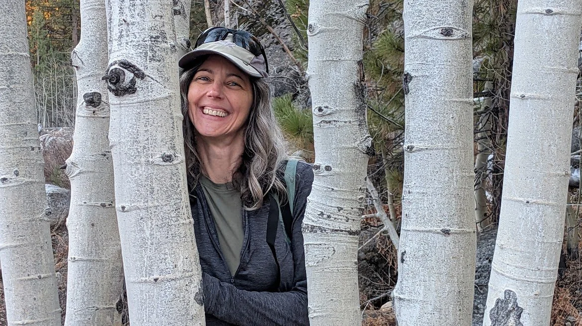 Andrea Broglio peeks out from between aspen trees