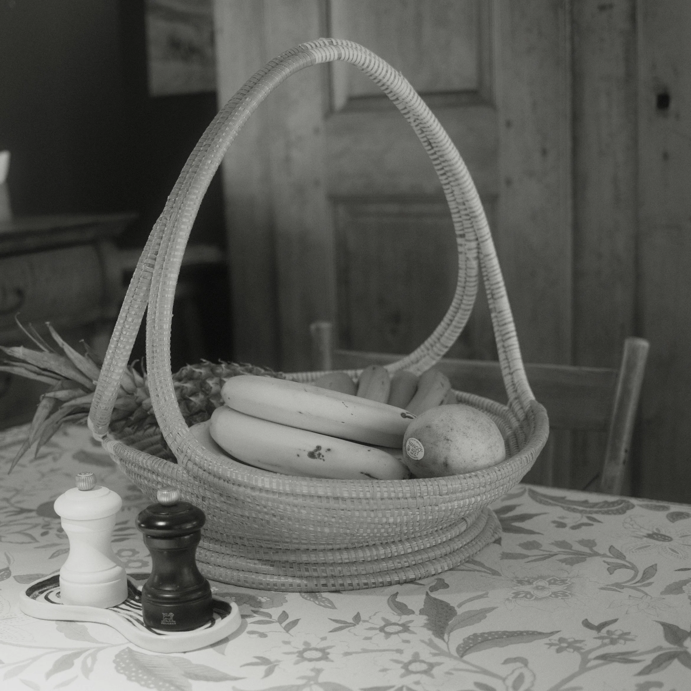 A decorative basket filled with various objects including black and white chess pieces, placed on a patterned tablecloth.