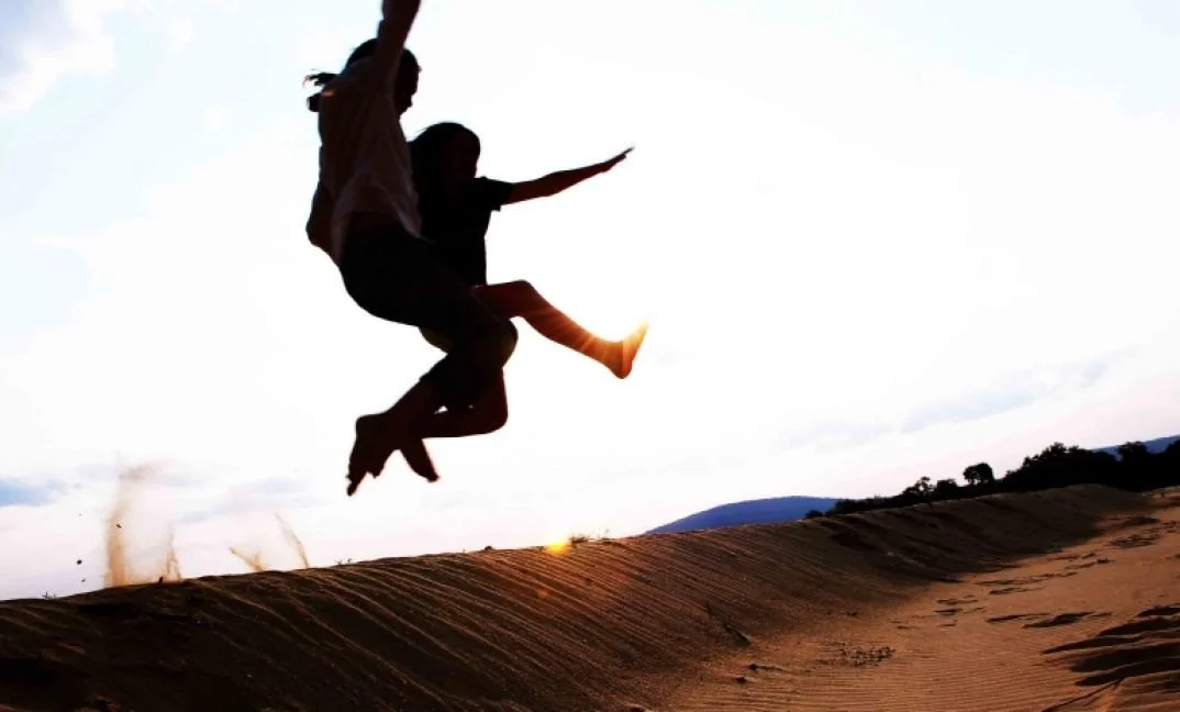 Georgie and her sister as children jumping off a sandbank in Nyerere National Park in Southern Tanzania
