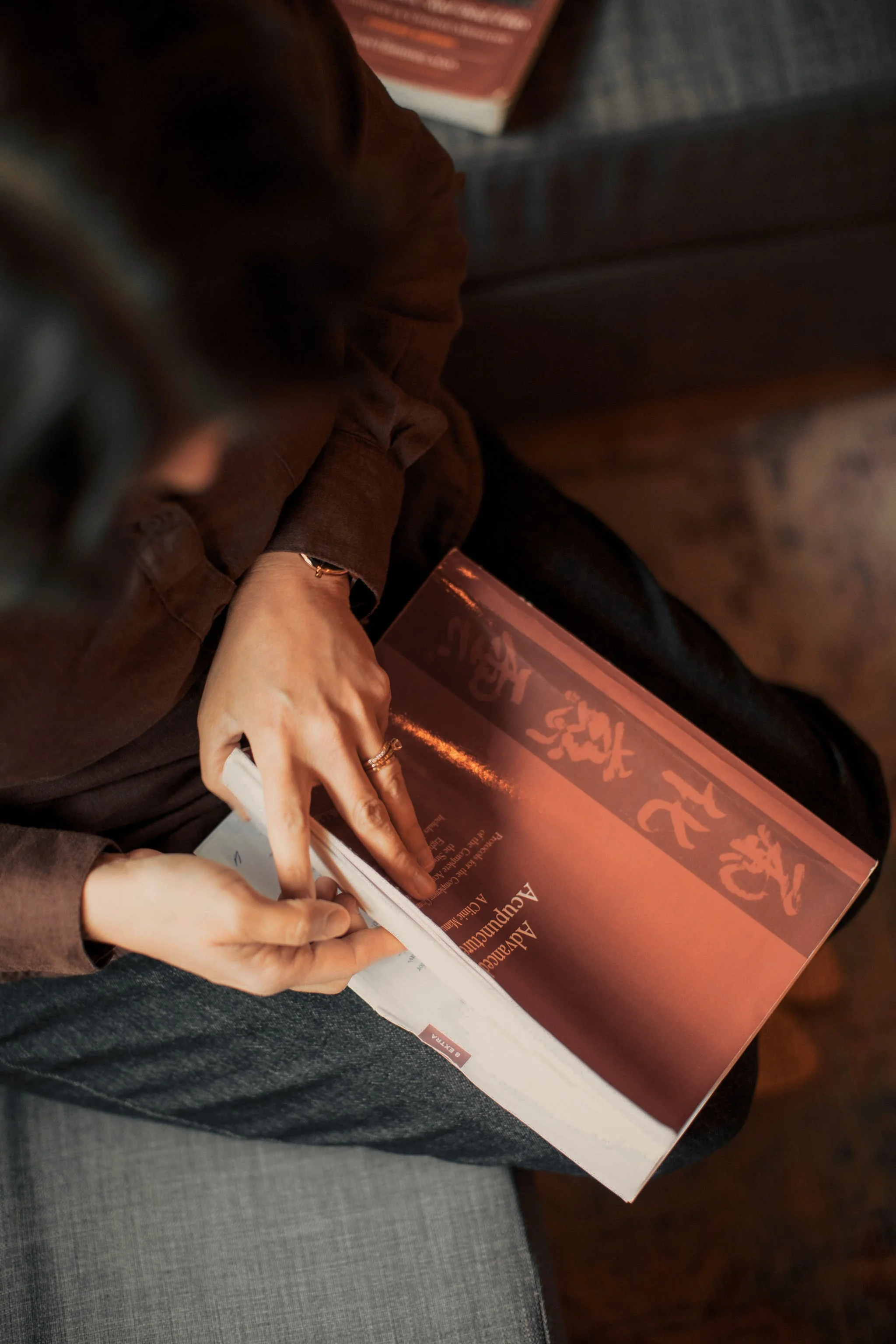 Person in brown jacket signing a book titled 'Asia' at a book signing event.