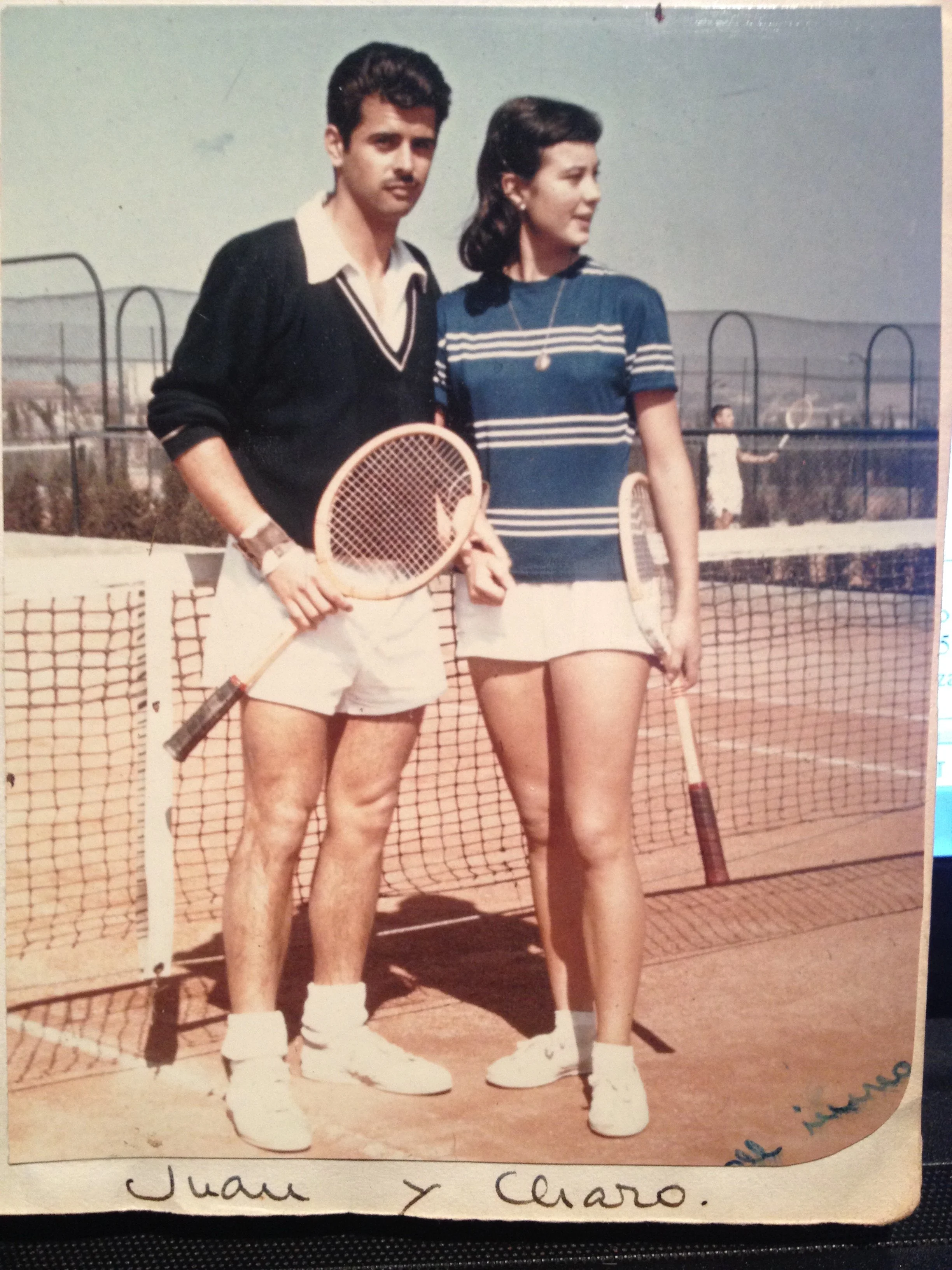 Una pareja de jóvenes en una cancha de tenis, sosteniendo raquetas y con ropa deportiva, parecen estar listos para jugar o en medio de un partido.