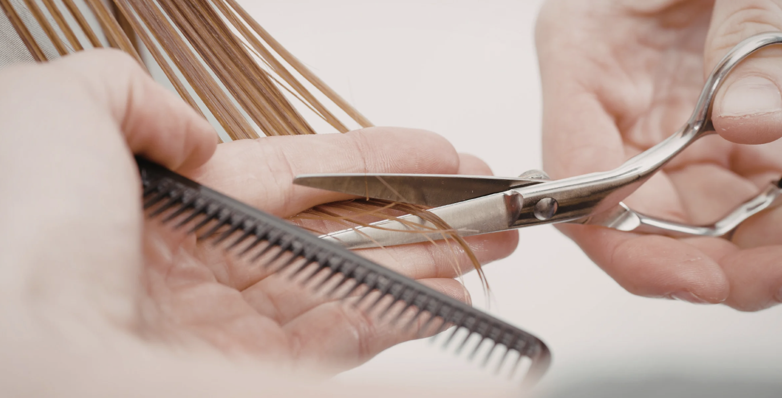 Person cutting hair with scissors while holding a comb.