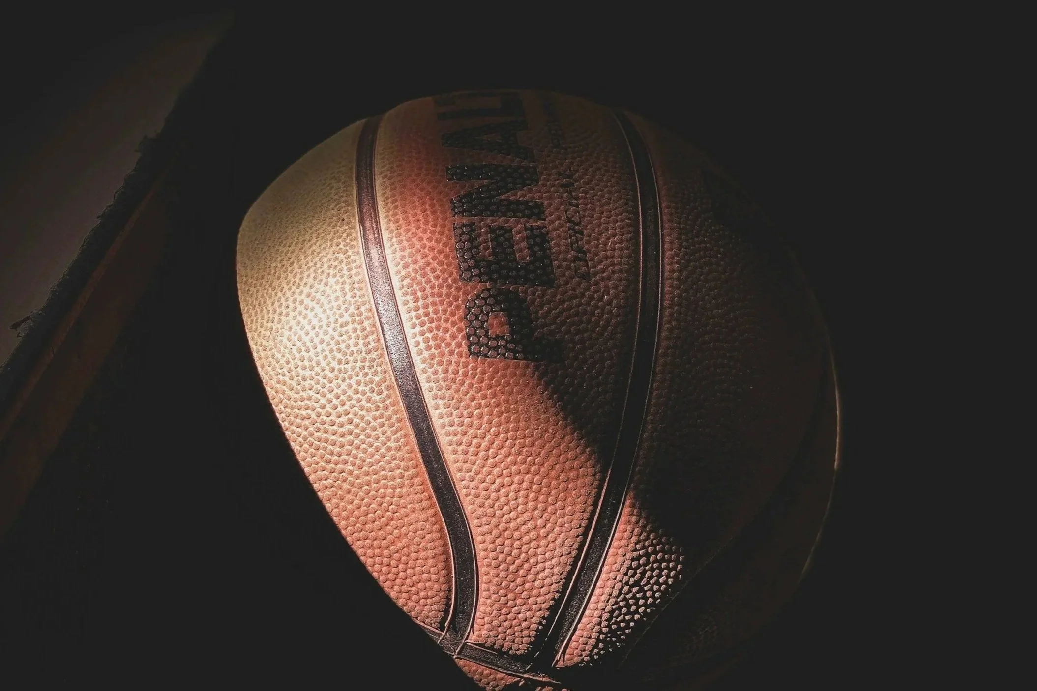 Close-up of a basketball ball with the brand name 'Wilson' on it, against a dark background.