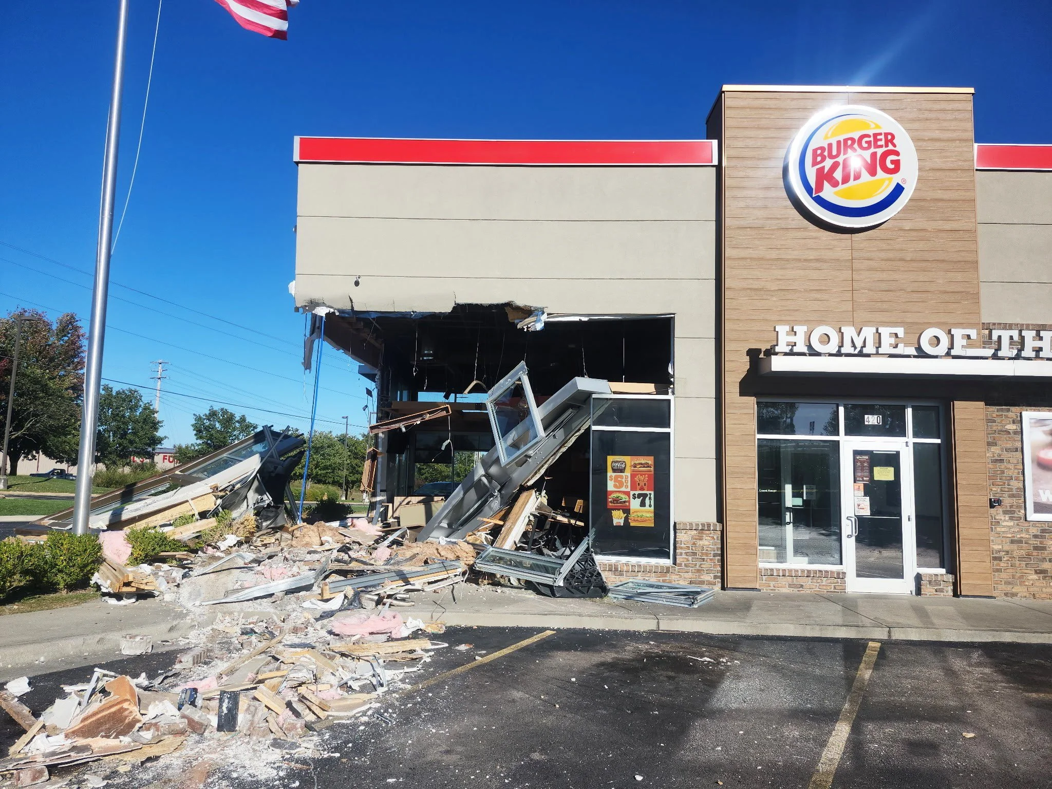 A Burger King restaurant with part of the front structure collapsed, debris and rubble on the sidewalk and parking lot, and a burnt or damaged section of the building's exterior, before The Board Up Company in St. Louis stabilized the structure.