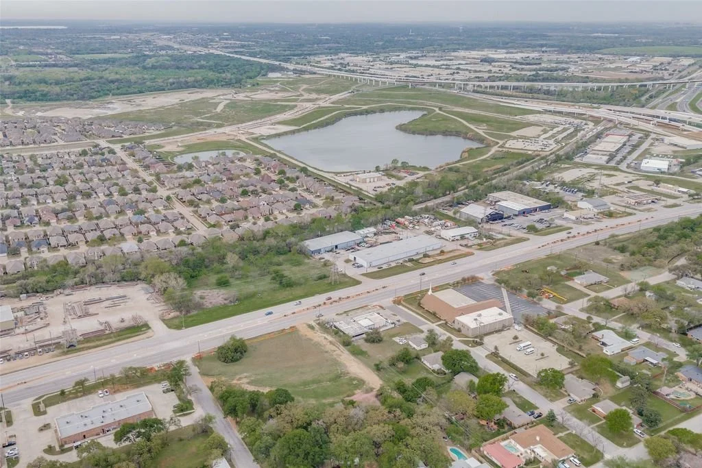 Aerial view of a suburban area with houses, a lake, and a highway.