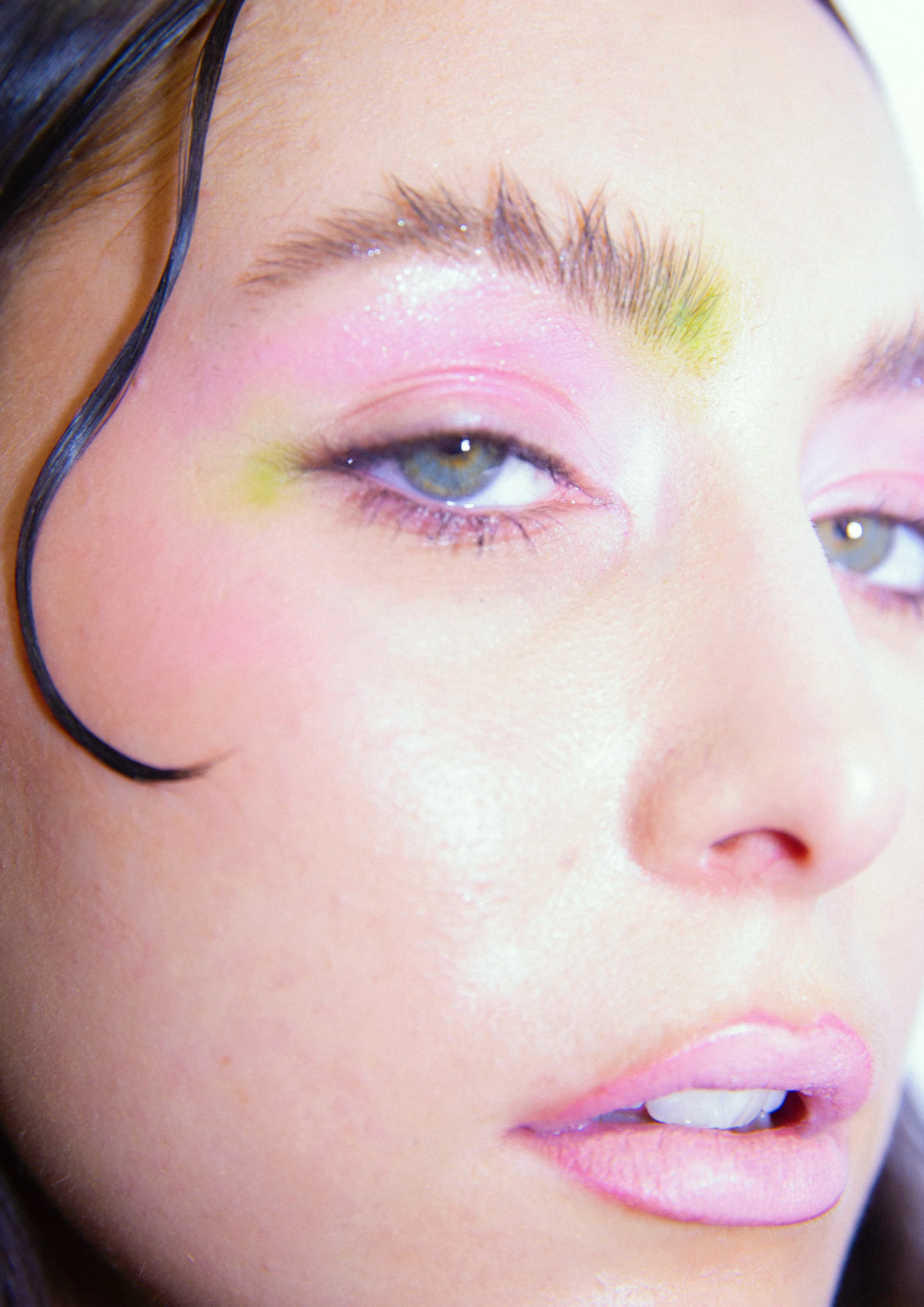 Close-up of a woman's face with makeup, showing her eye, lips, and partially visible nose, with dark hair and a natural skin tone.