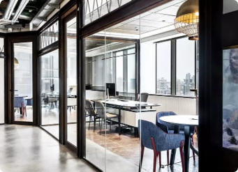 Modern office space with glass walls, desks, chairs, and city skyline view