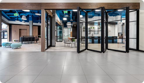 Modern lobby entrance with glass doors, seating area, and open floor with tiled surface.