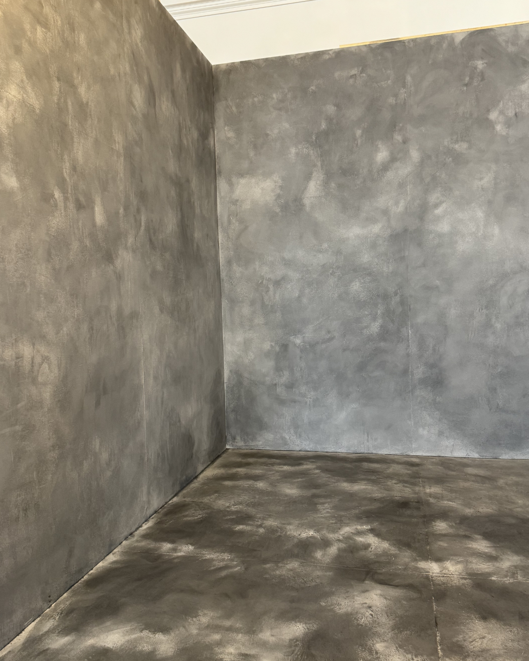 Empty corner with unfinished concrete walls and floor in a room under construction or renovation.