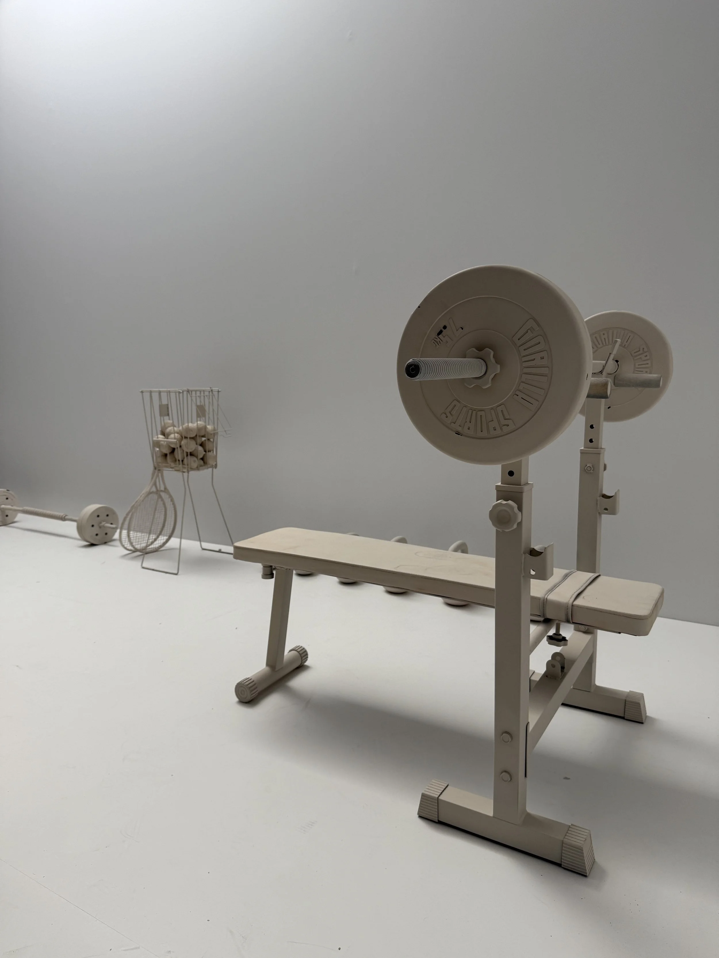 An empty medical examination or treatment room with specialized equipment, including an examination table, a weight scale, and a basket with rolled towels.