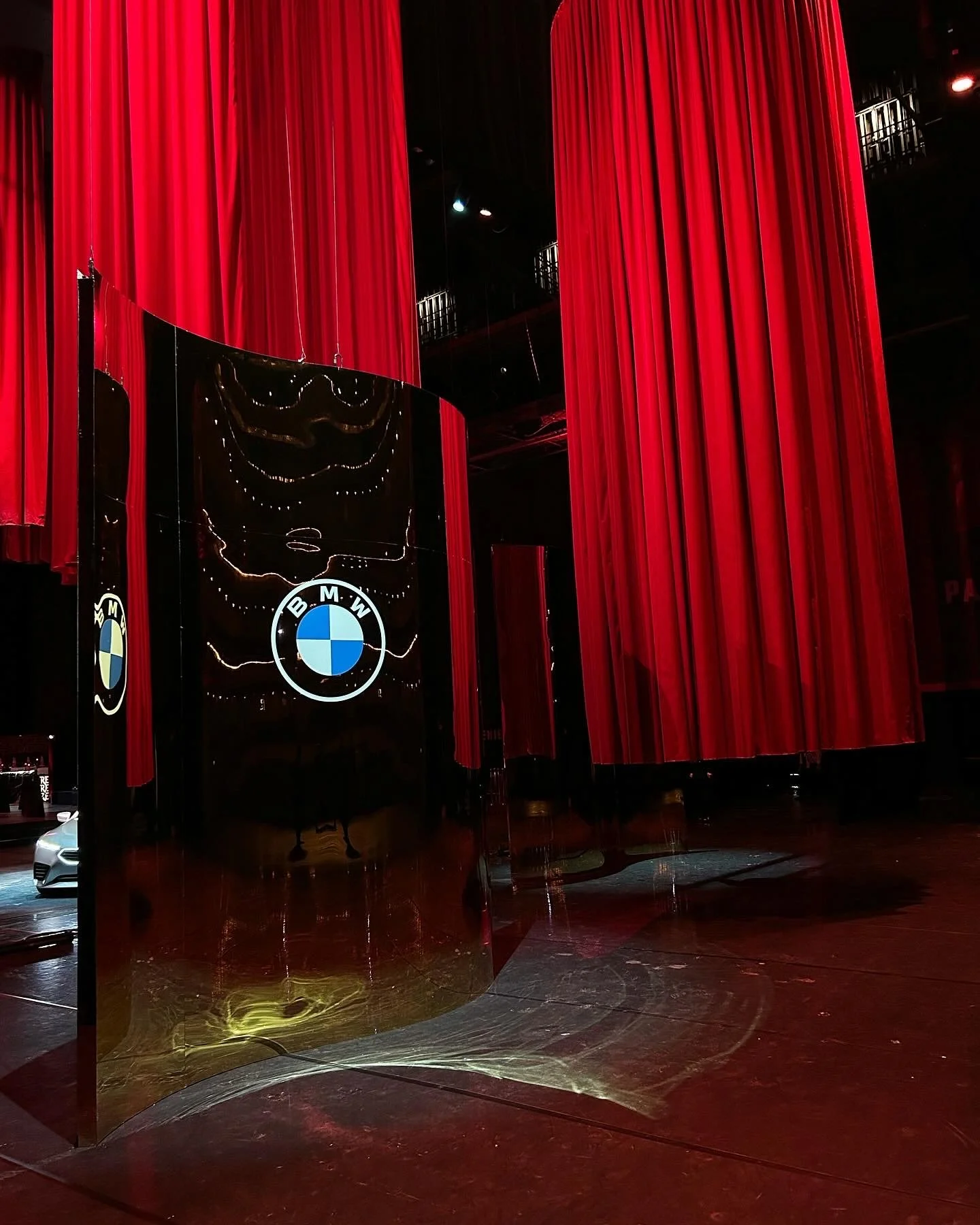 Red stage curtains with black and BMW logo display in front.