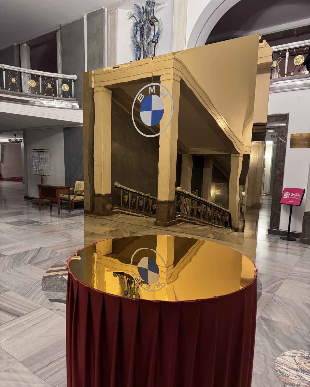 Reflective art piece with BMW logo in an elegant hotel lobby.
