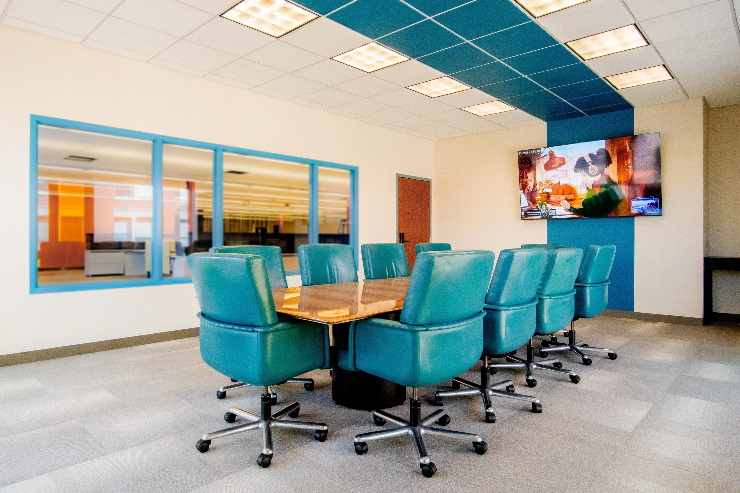board room with teal office chairs around a large wooden table