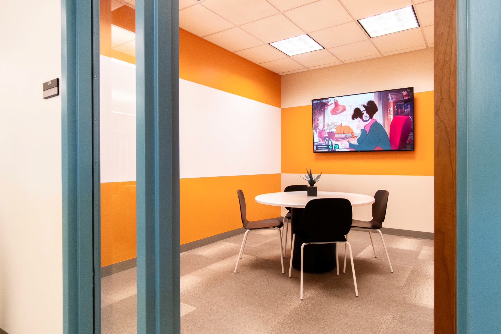 private meeting room space with yellow walls and chairs around a white table. tv on the wall