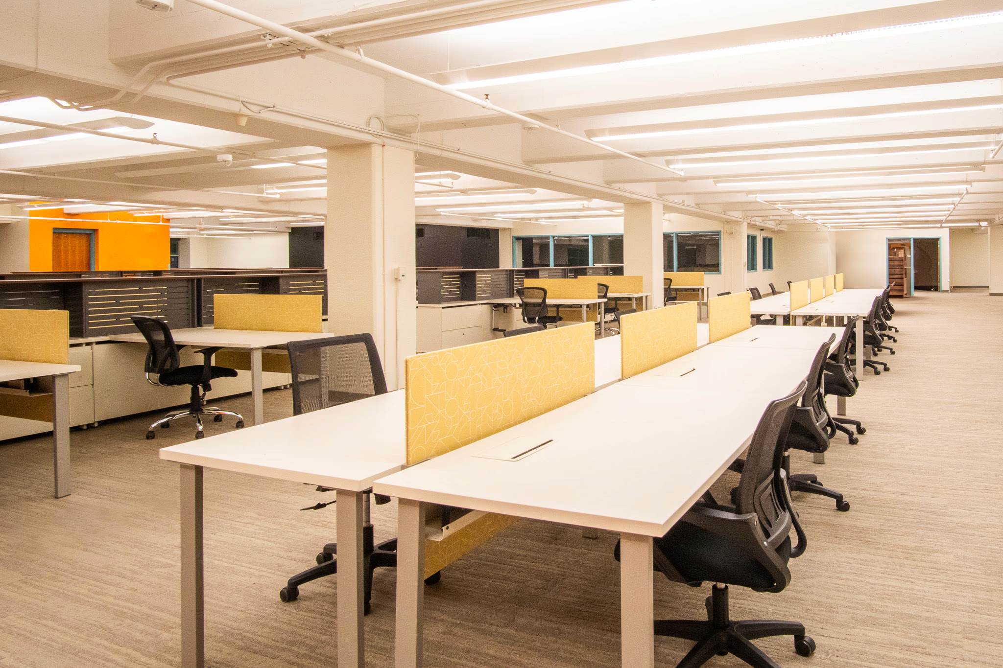 second floor day pass of tech central with white office tables with yellow dividers and black office chairs
