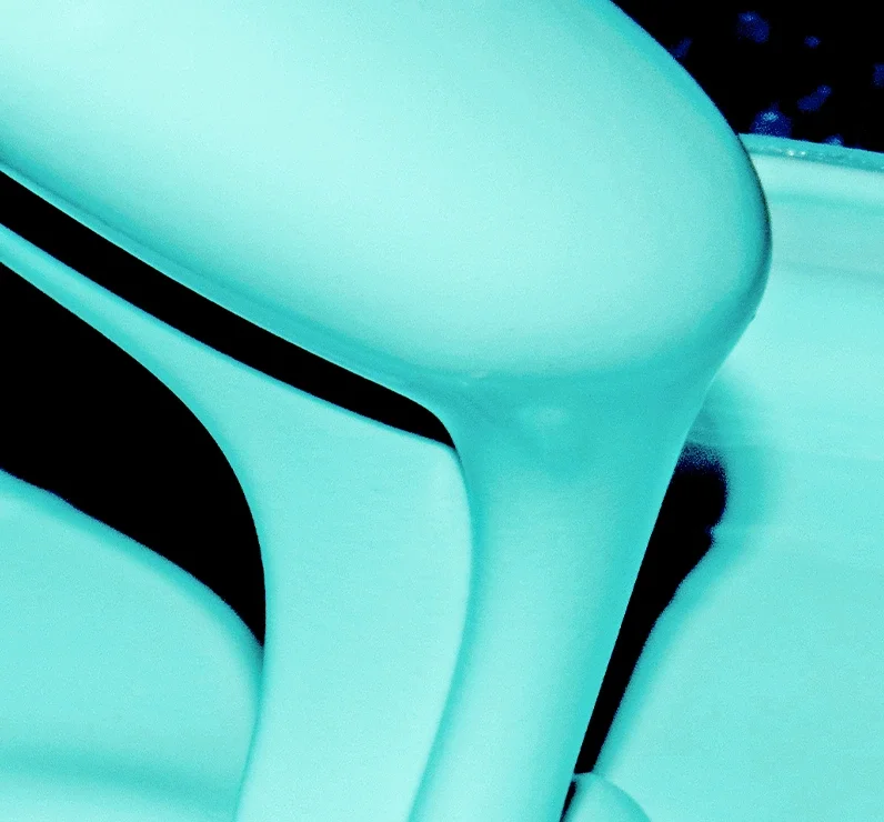 Close-up of a modern, light blue sculpture with smooth, flowing curves against a dark background.