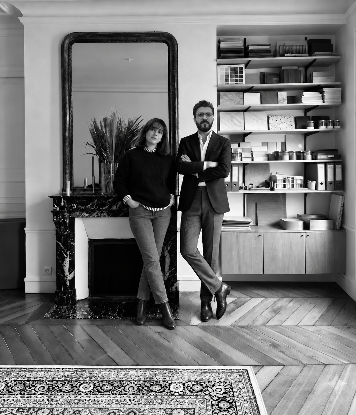 Deux personnes, un homme en costume et une femme en pull, posent dans un intérieur élégant avec un miroir et une materiauthéque.