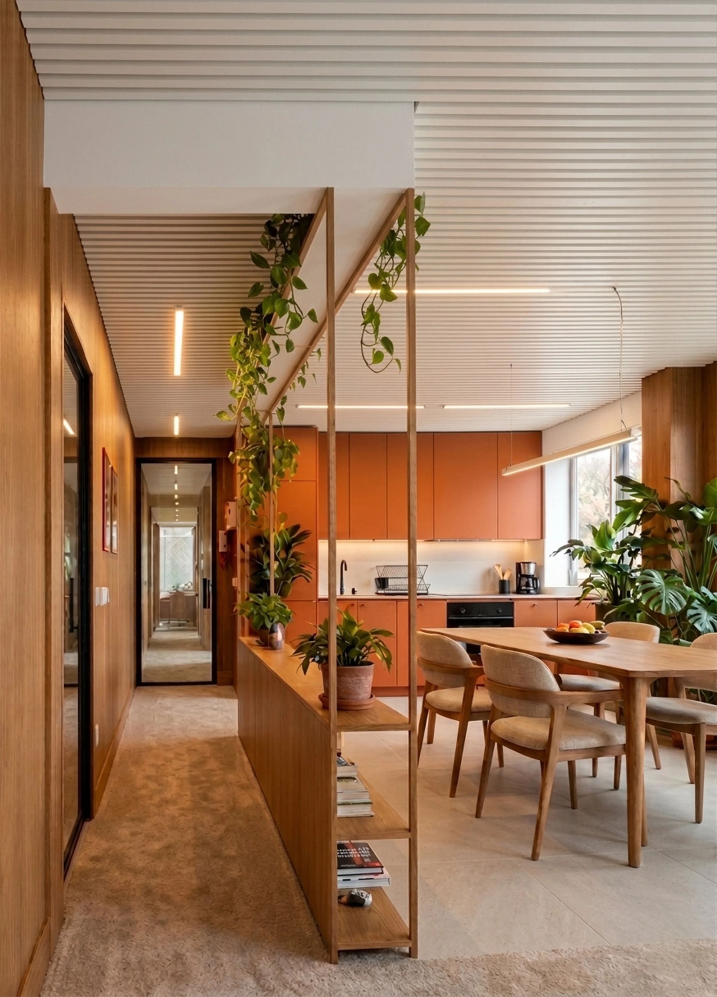 Intérieur moderne d'une cuisine avec mobilier en bois, table ronde avec chaises, étagères, plantes et éclairage naturel.