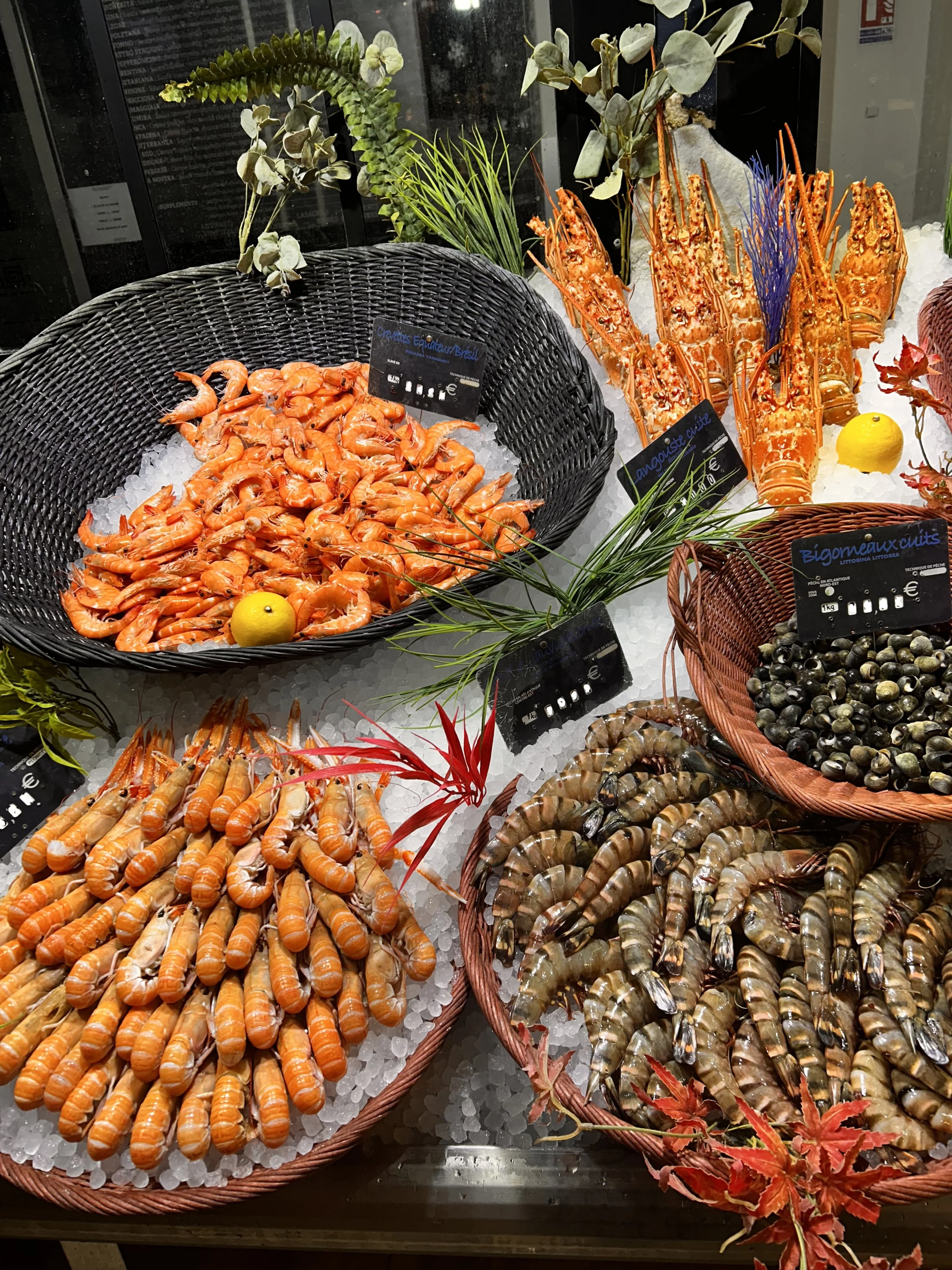 Un étalage de fruits de mer, avec des crevettes, des homards et des coquillages, exposés sur de la glace, décoré de feuilles d'automne.