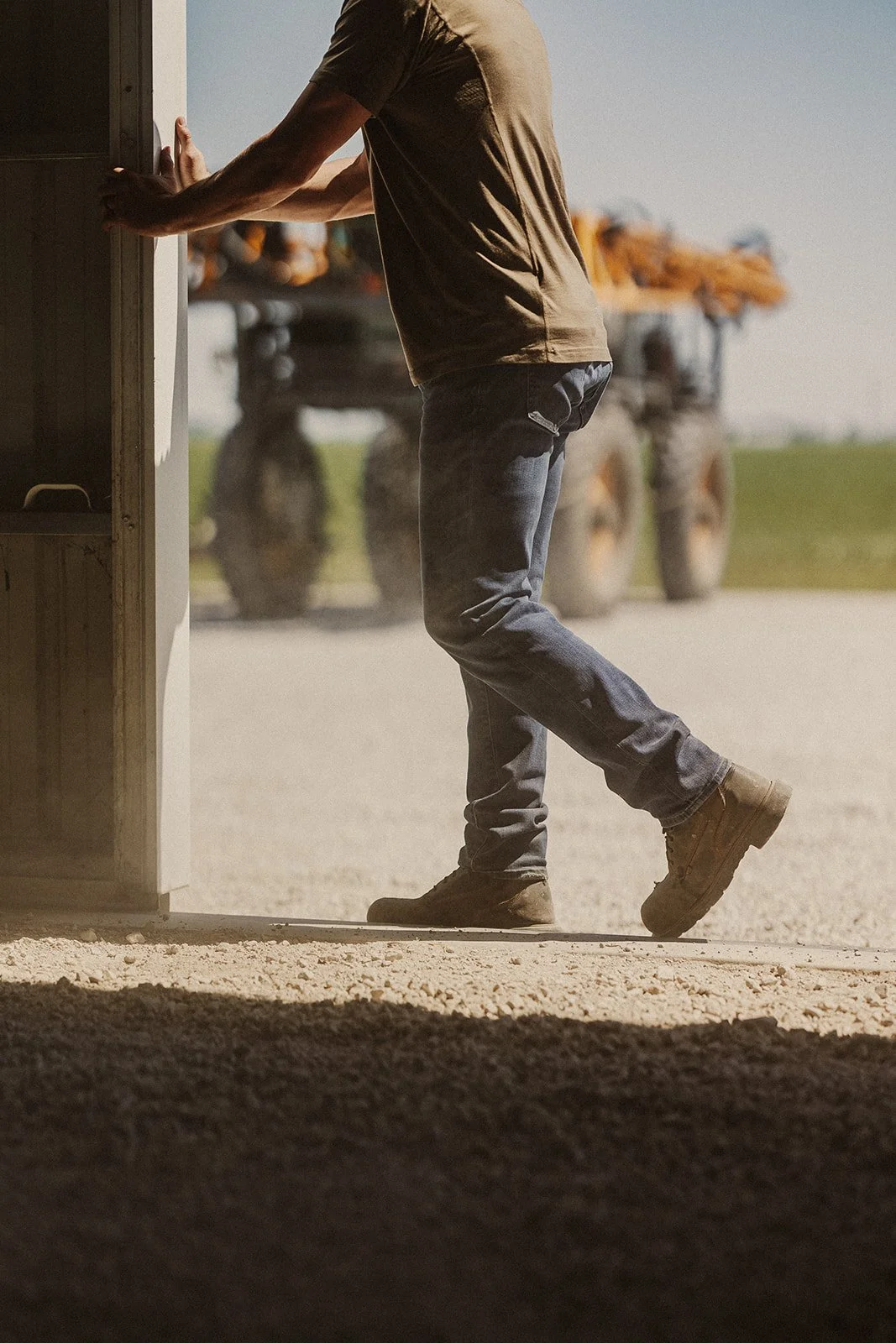 Person pushing open a door at a farm with tractors in the background.