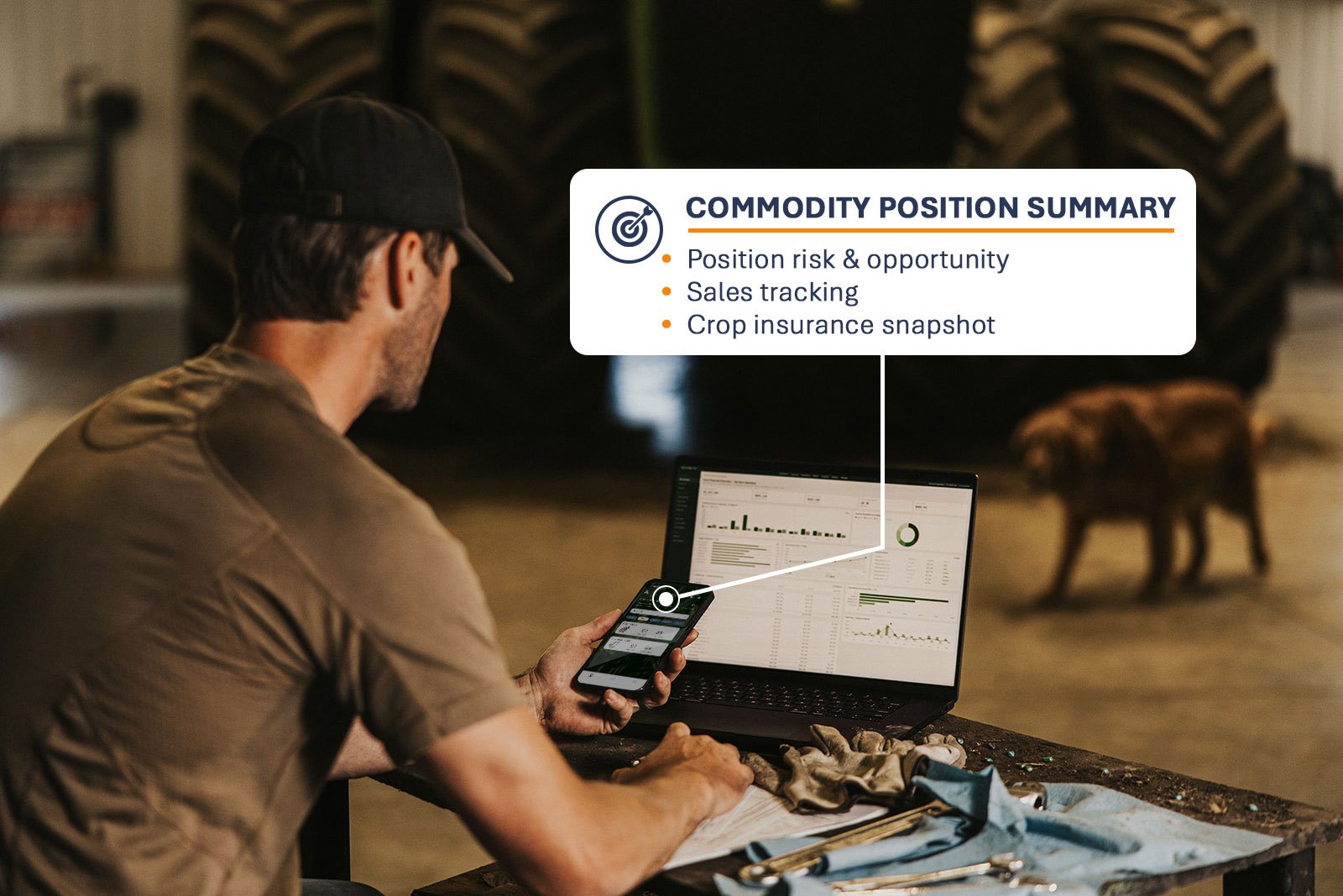 A man wearing a black cap and brown T-shirt is working with a smartphone and laptop in an industrial setting, with a large tire and a cow in the background. A graphic overlay displays a
