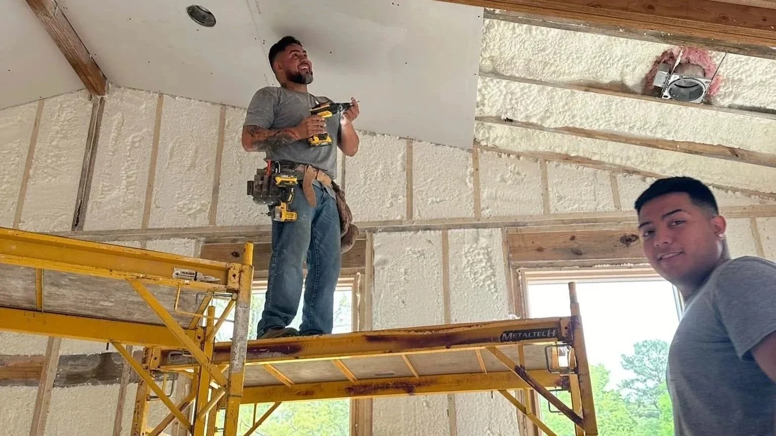 Innovative Renovations Project Manager, Daniel, and another employee installing sheetrock in a newly insulated home addition.