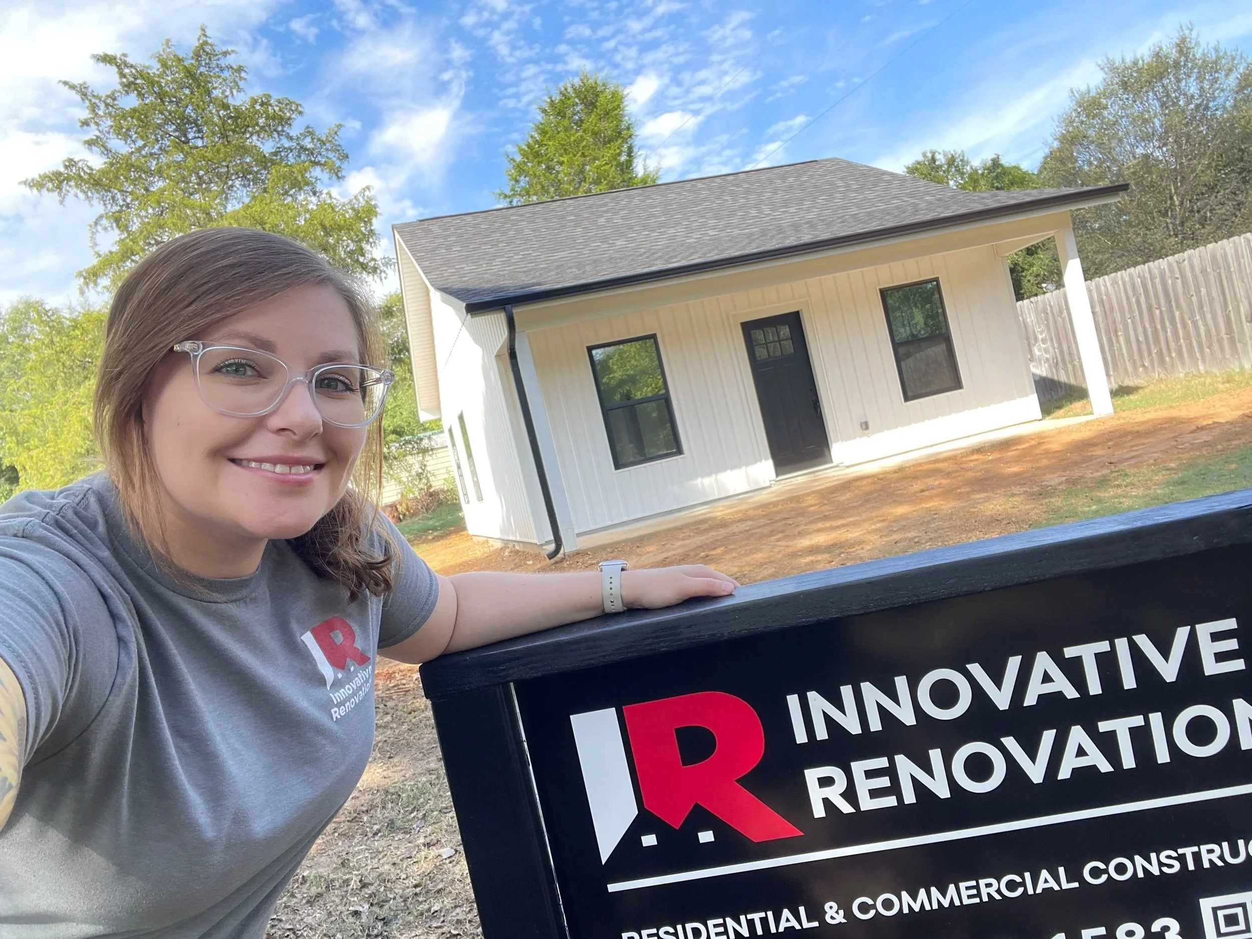 Kim Morrella, owner of Innovative Renovations, posing outside of a new construction build with the Innovative Renovations yard sign