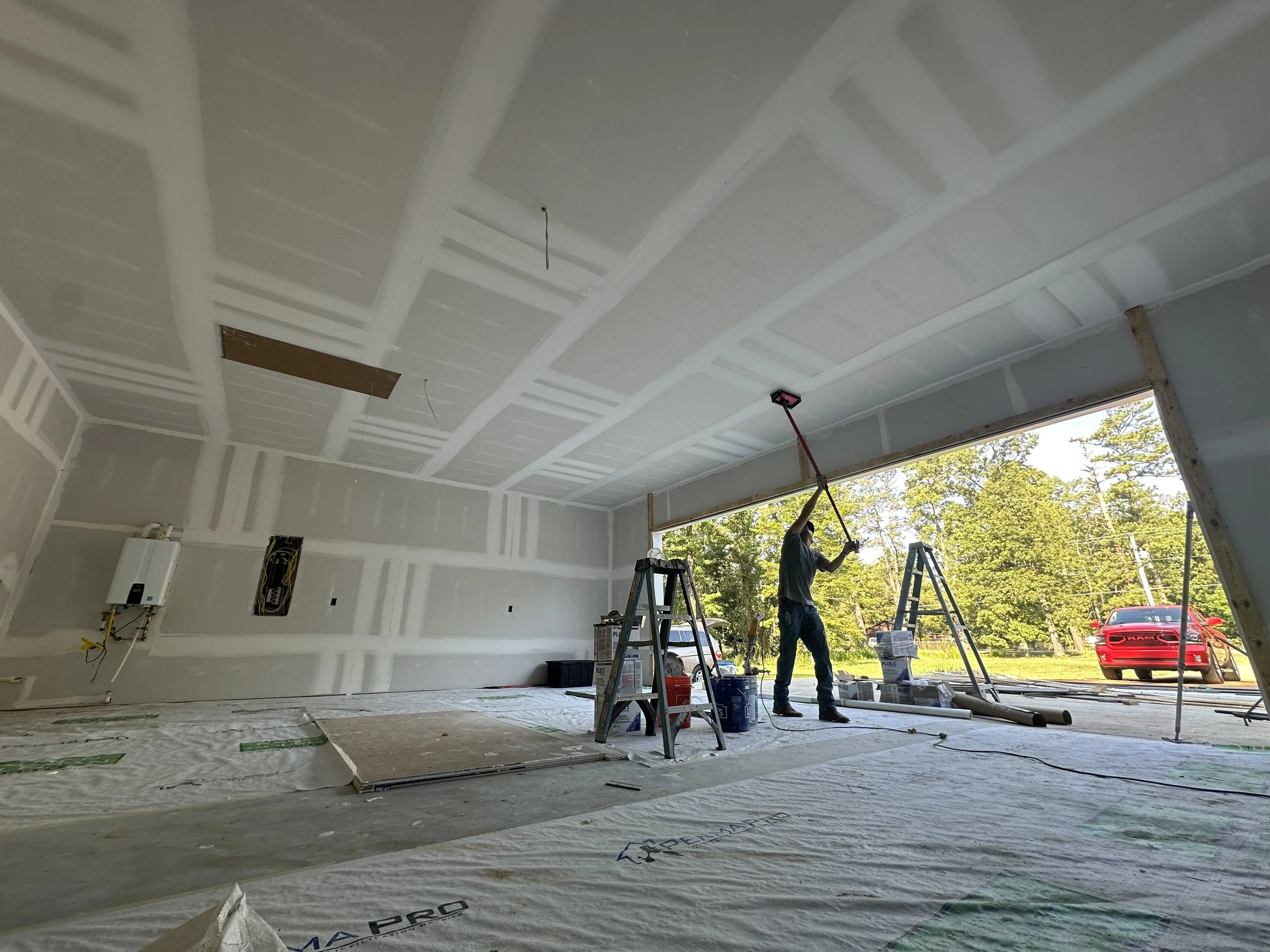 Crew member sanding new sheetrock to prep for texture and paint