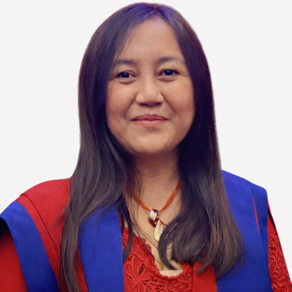 A woman with long dark hair, wearing a red top and a blue academic gown, smiling at the camera.