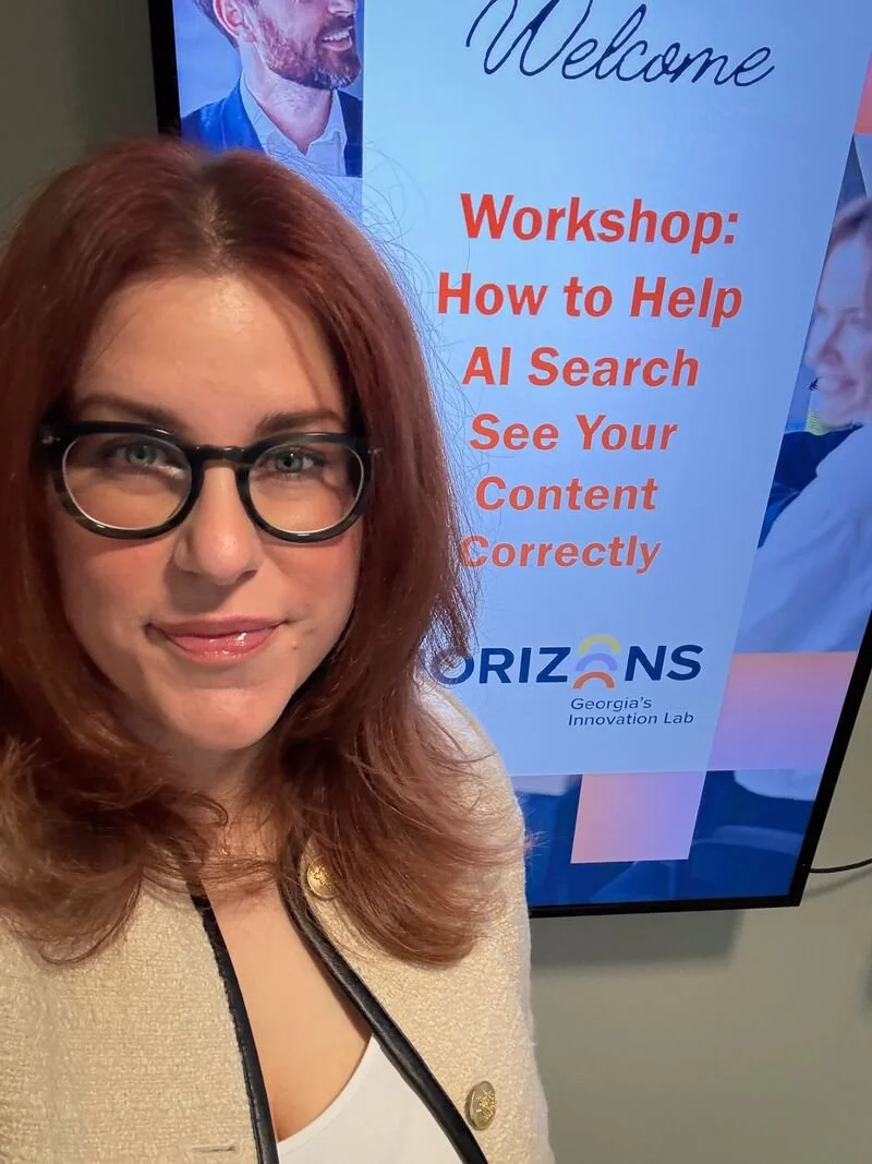 Amanda standing in front of a sign that reads Workshop How to Help AI Search See Your Content