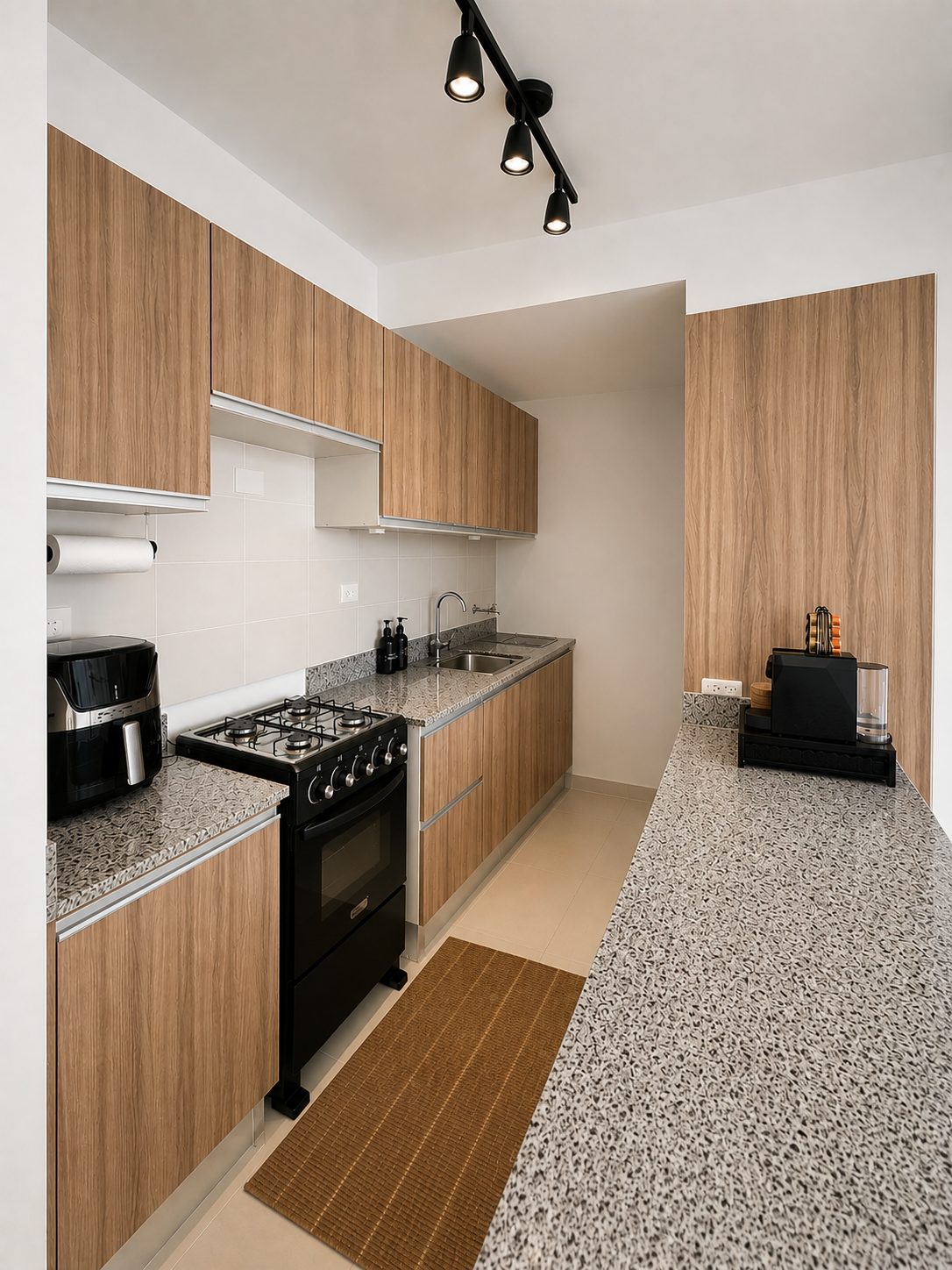 Modern kitchen with wooden cabinets, granite countertops, and a black stove, coffee maker, and toaster.
