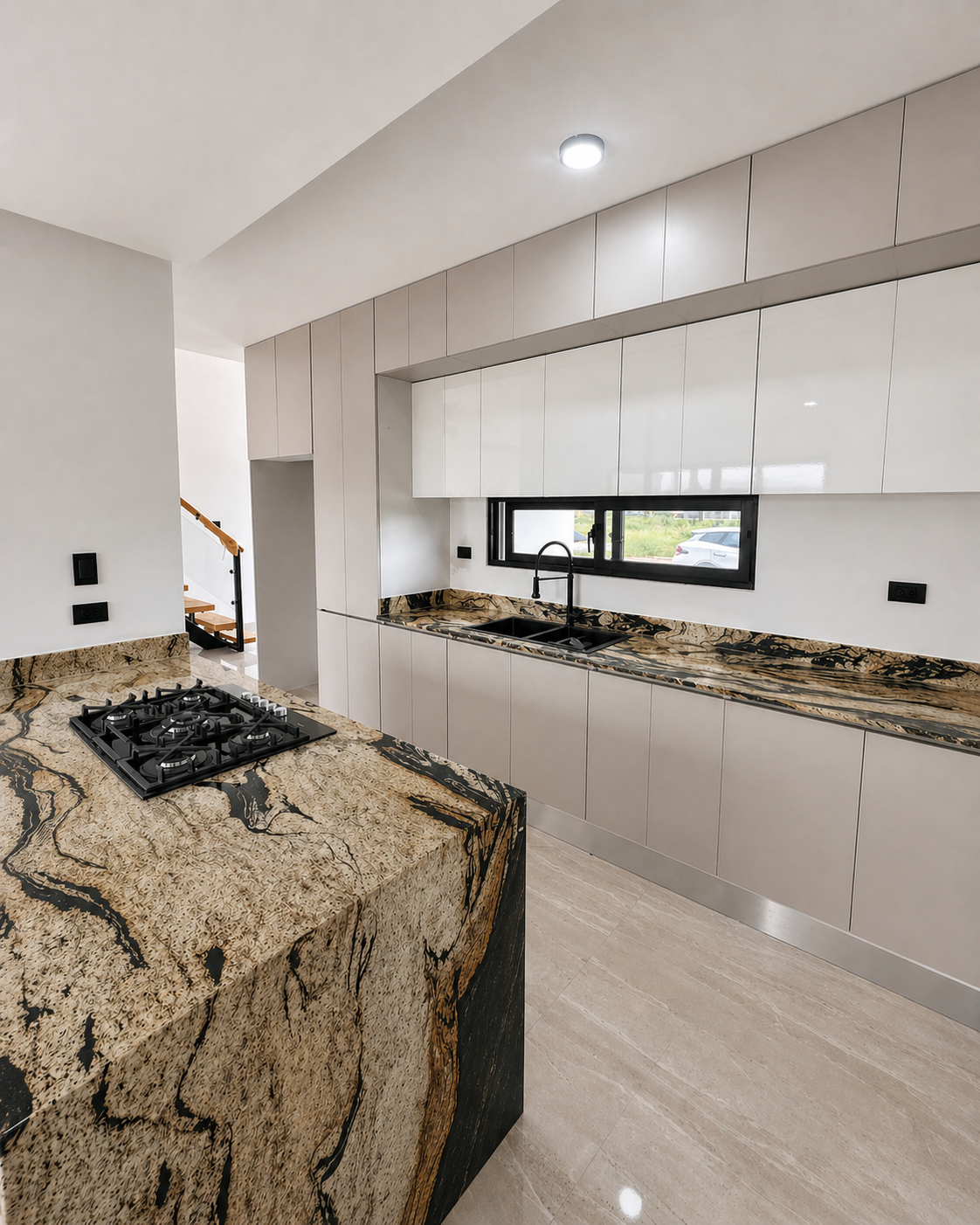 Modern kitchen with black and gold marble countertops, white cabinets, a black window, and a kitchen sink with a black faucet.