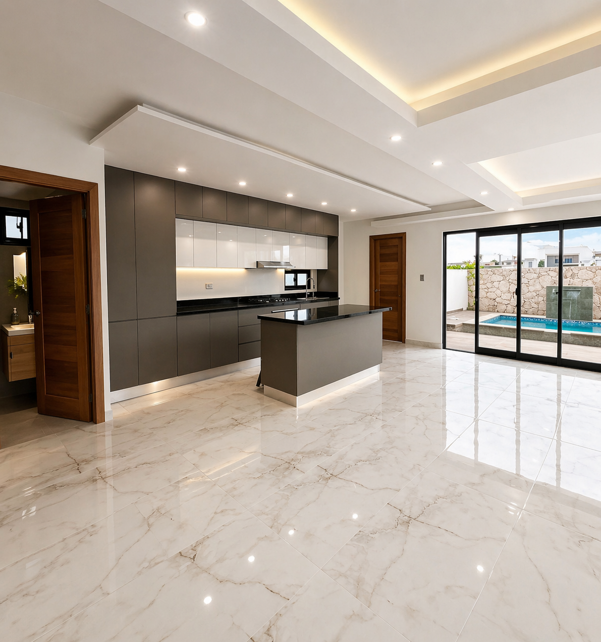 Modern kitchen with black countertops, gray cabinets, a small island, and large sliding glass doors leading to an outdoor pool area.