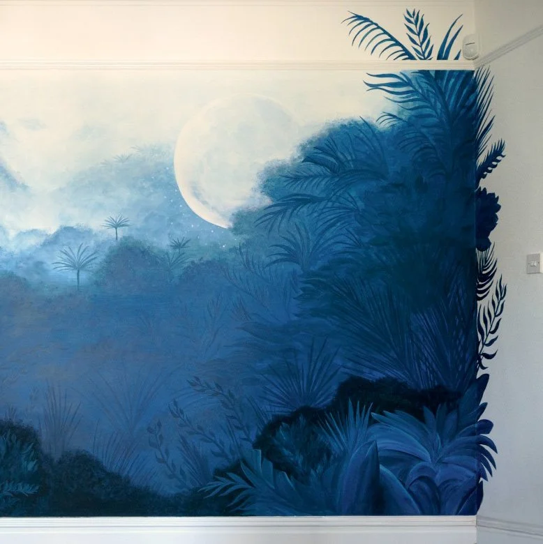 A mural of a misty landscape with a full moon, tropical plants, and trees painted in shades of blue and white.