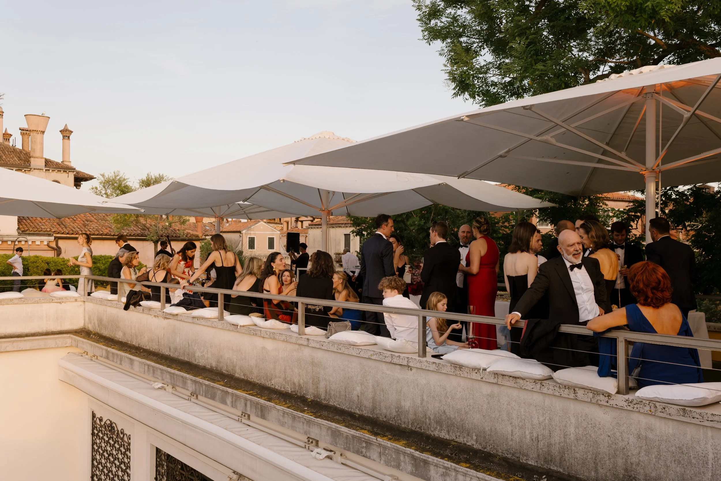 Atmospheric welcome cocktail party on a Venetian rooftop terrace with international guests.
