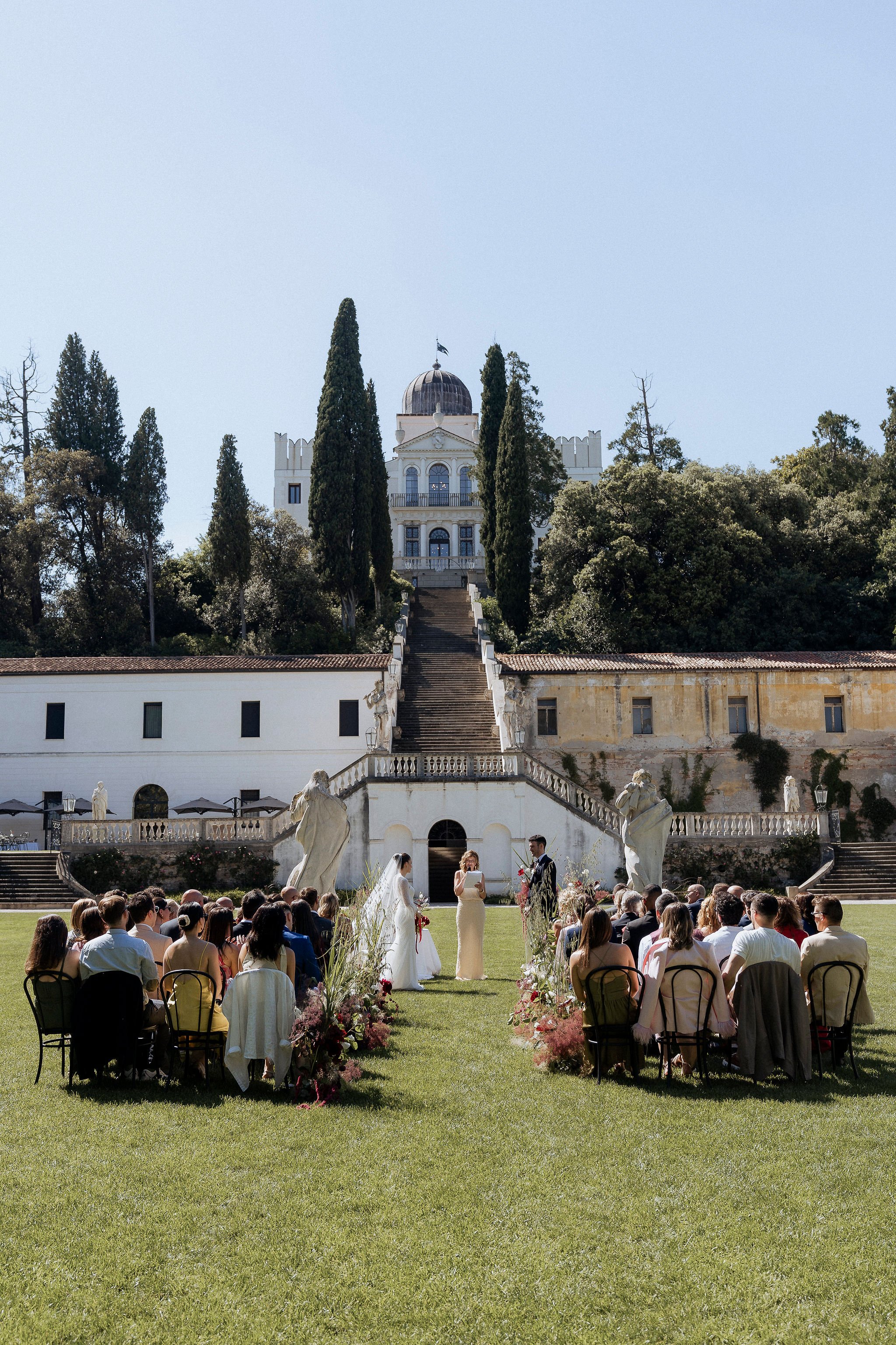 Outdoor wedding ceremony on the lawn at Villa Selvatico with the monumental staircase in the background and all the guests.