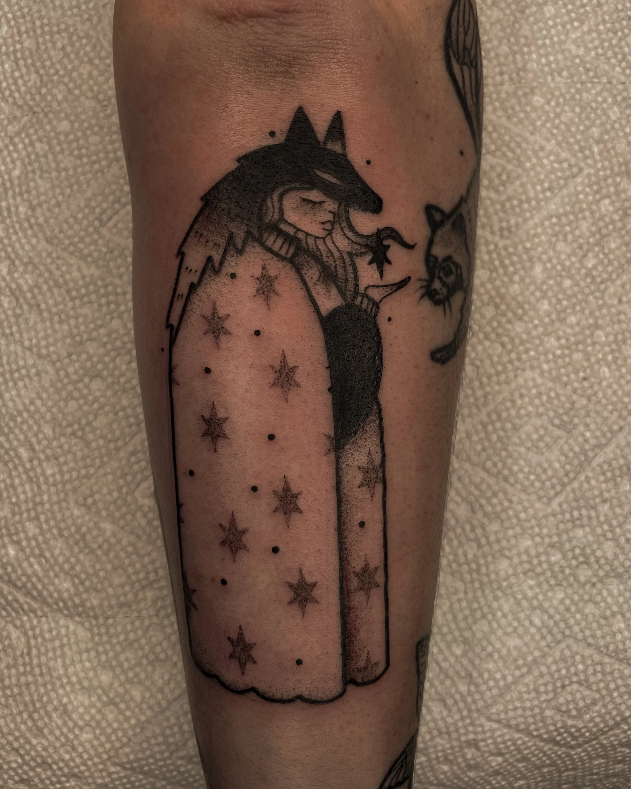 Tatouage d'une femme avec un manteau et un chapeau, entourée d'étoiles, sur une peau