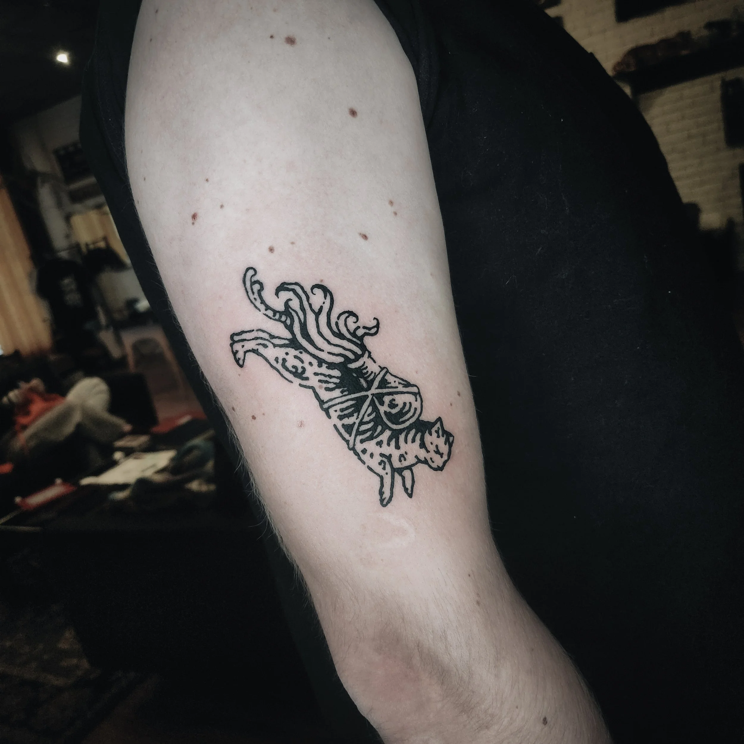 Tatouage d'une octopus sur l'avant-bras d'une personne, photographié dans un intérieur sombre.