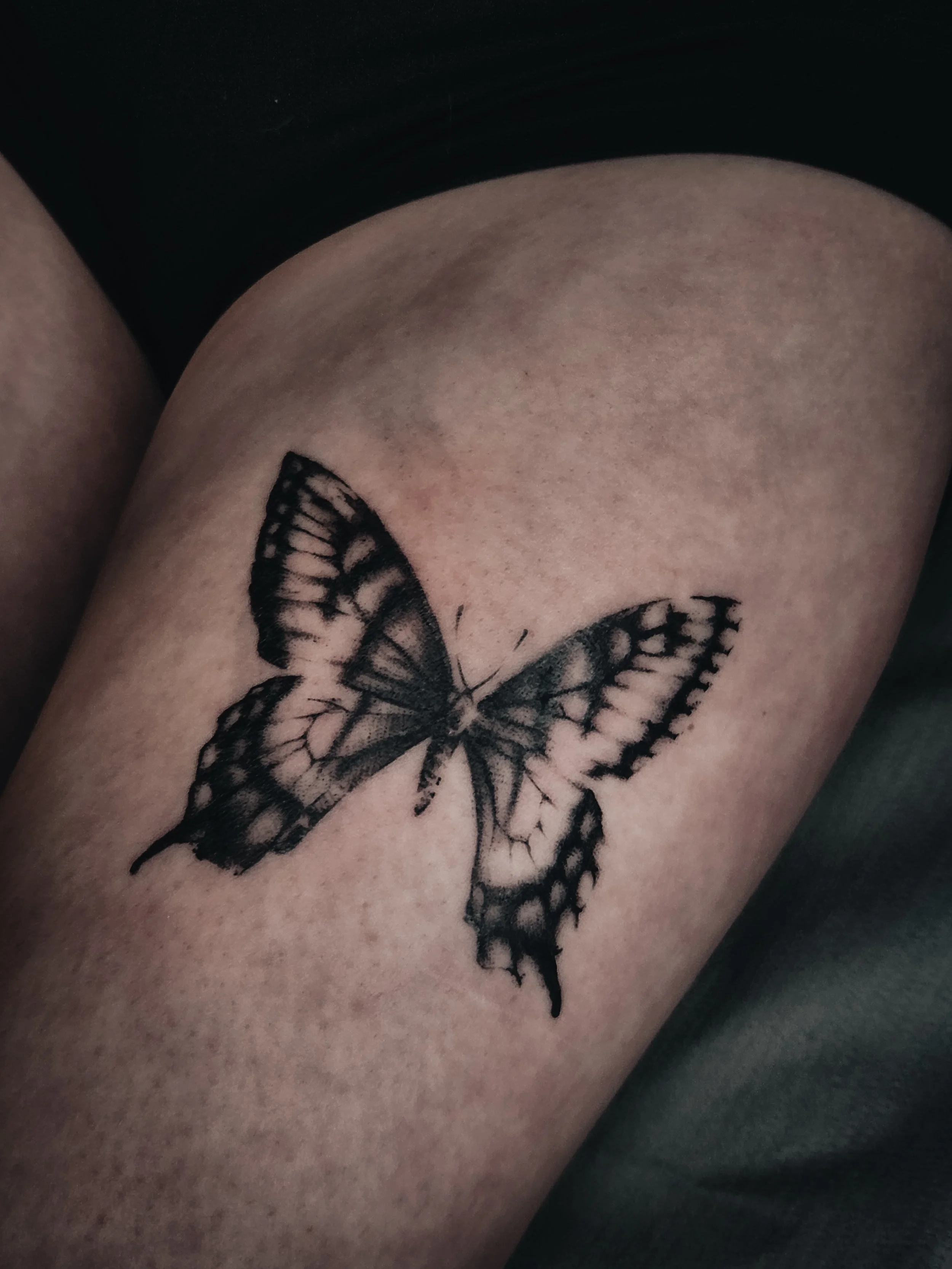 Tatouage d'un papillon noir sur la peau nue.