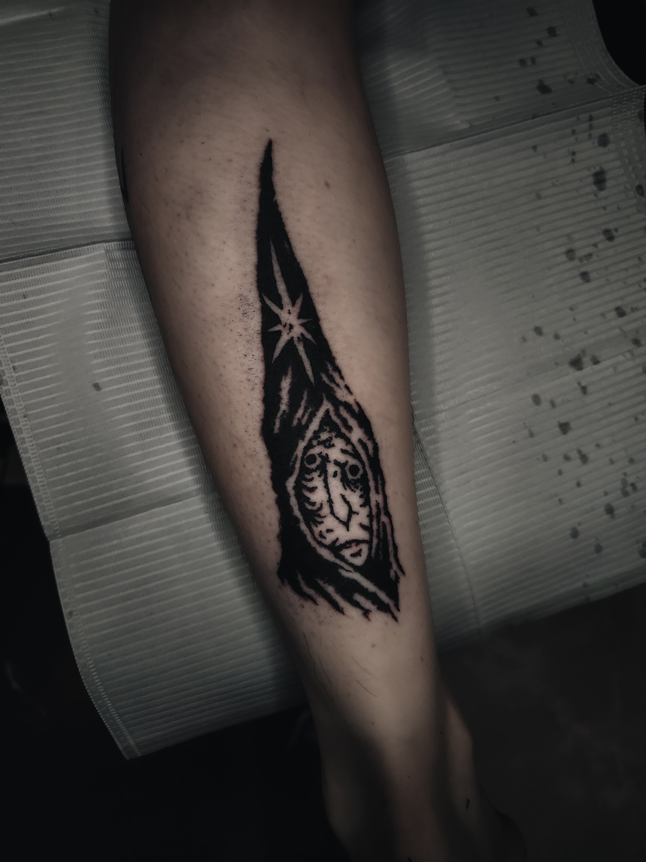 Tatouage encre noir d'une tête de tribu africaine ou amérindienne sur une jambe humaine.