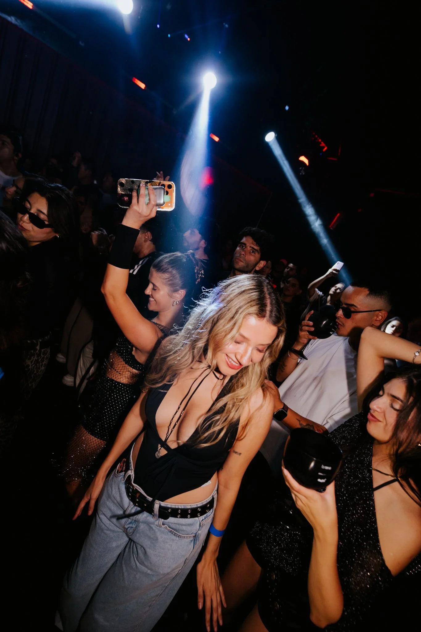 People dancing and enjoying music at a nightclub with colorful lighting.