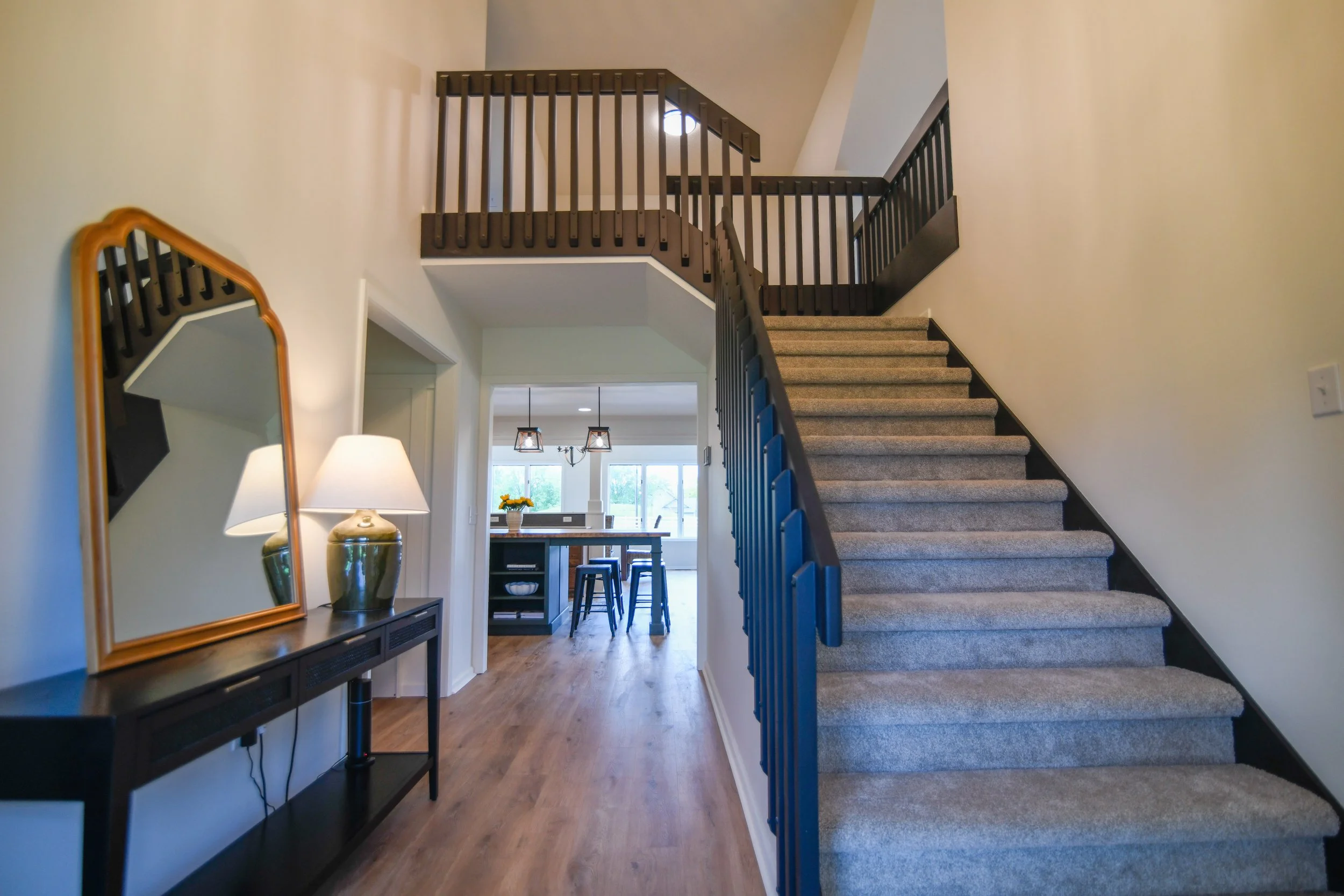 Grand front entry with sightlines straight through to the kitchen, living room to the right, and an expansive upstairs landing leading to the bedrooms above