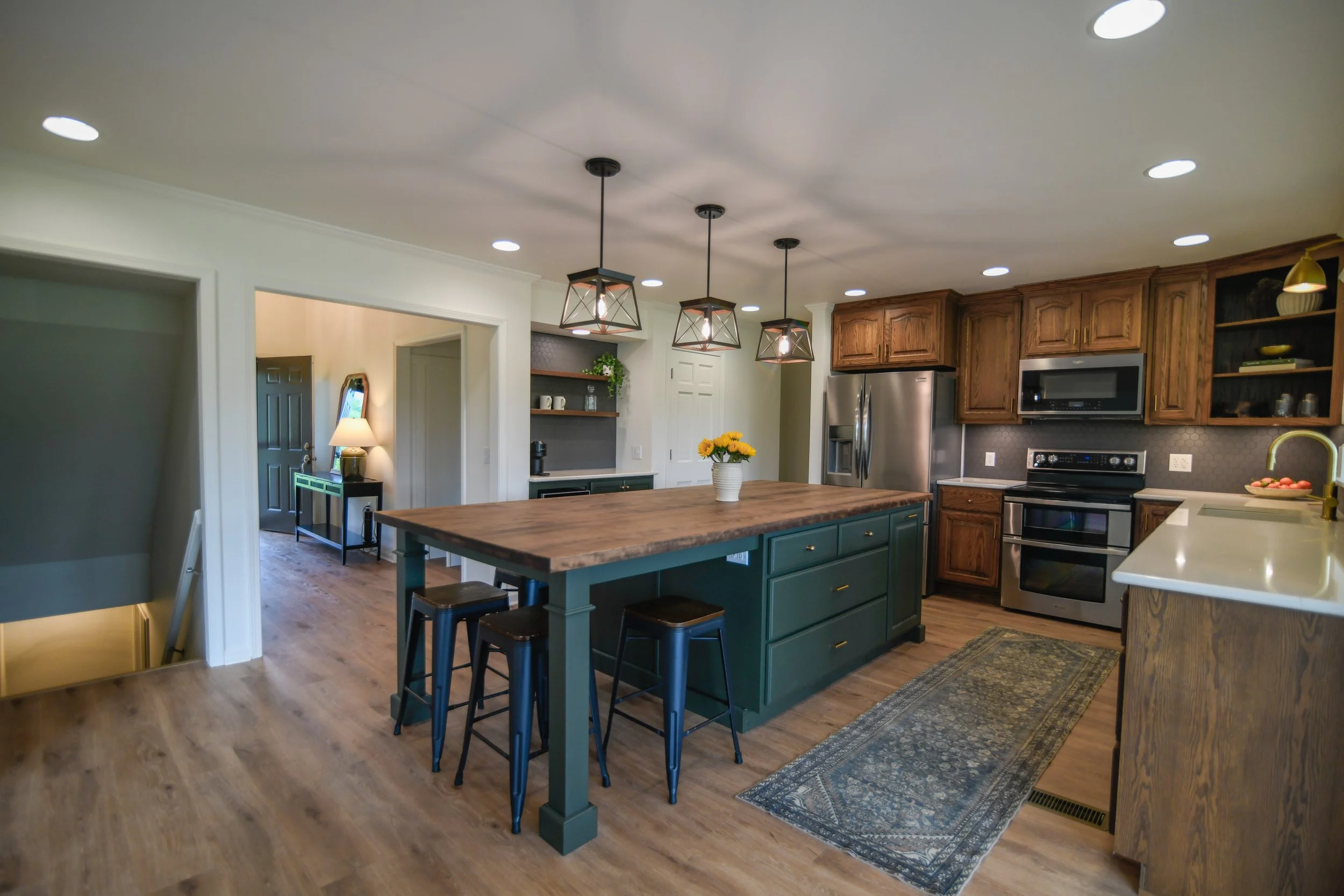 The true heart of the home — this open-concept kitchen features a spacious 9-foot island, rich hardwood cabinetry, convenient access to the lower level, and seamless views into both the living and dining rooms