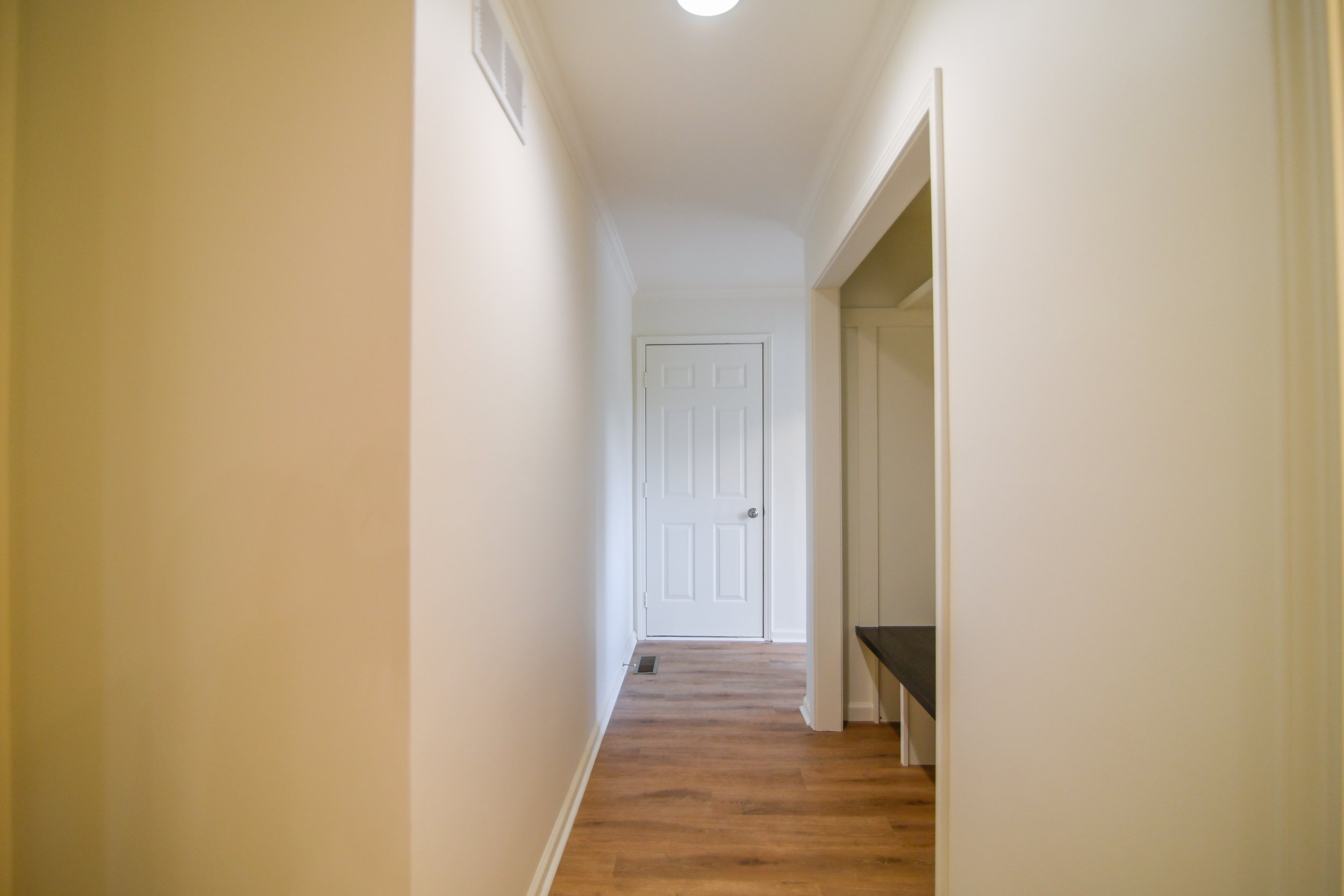 Functional hallway connecting the kitchen and garage, featuring an open-concept drop zone with built-in storage perfect for backpacks, coats, and everyday organization