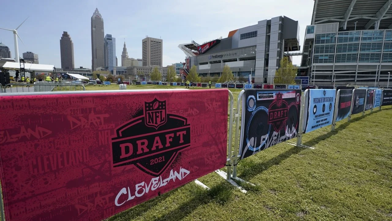 Barriers with NFL Draft 2021 logos outside a stadium with a city skyline in the background.