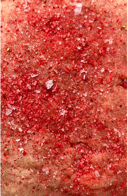 Close-up of a strawberry cookie surface covered with salt, sugar and freeze-dried strawberry powder.
