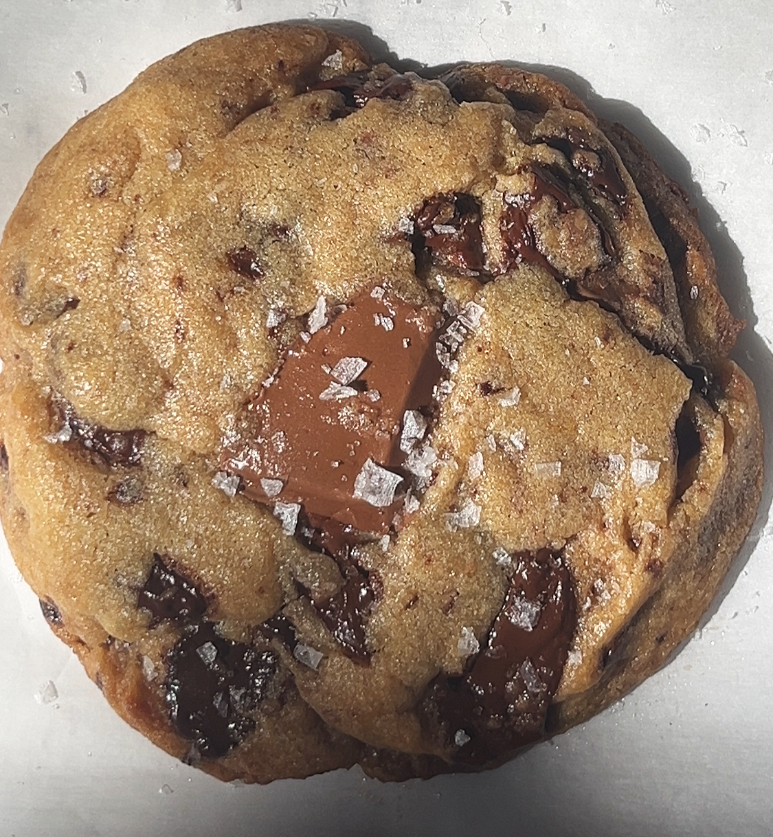 Chocolate chip cookie with a piece of chocolate and sea salt on top.