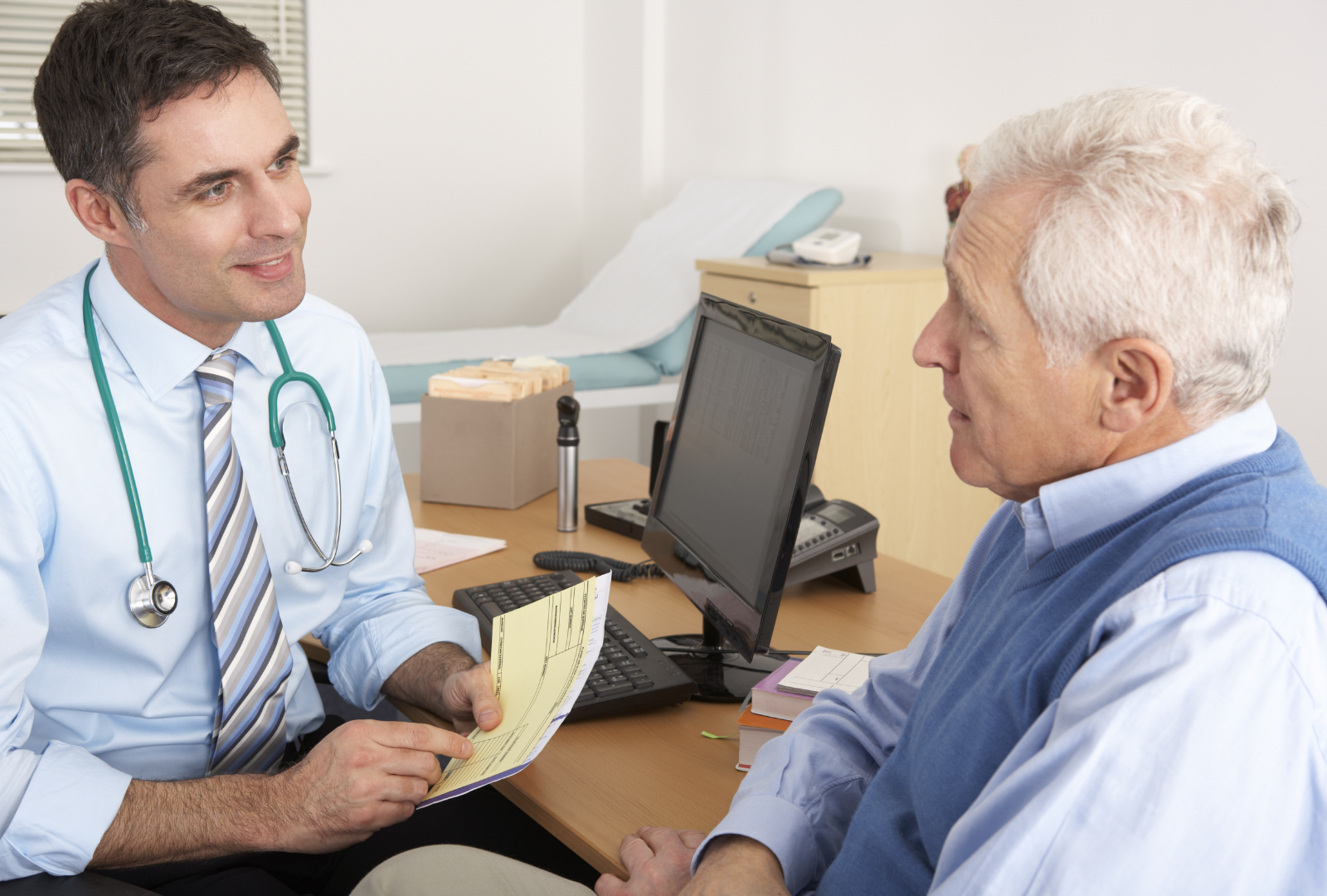 Doctor talking to an elderly male patient in a medical office.