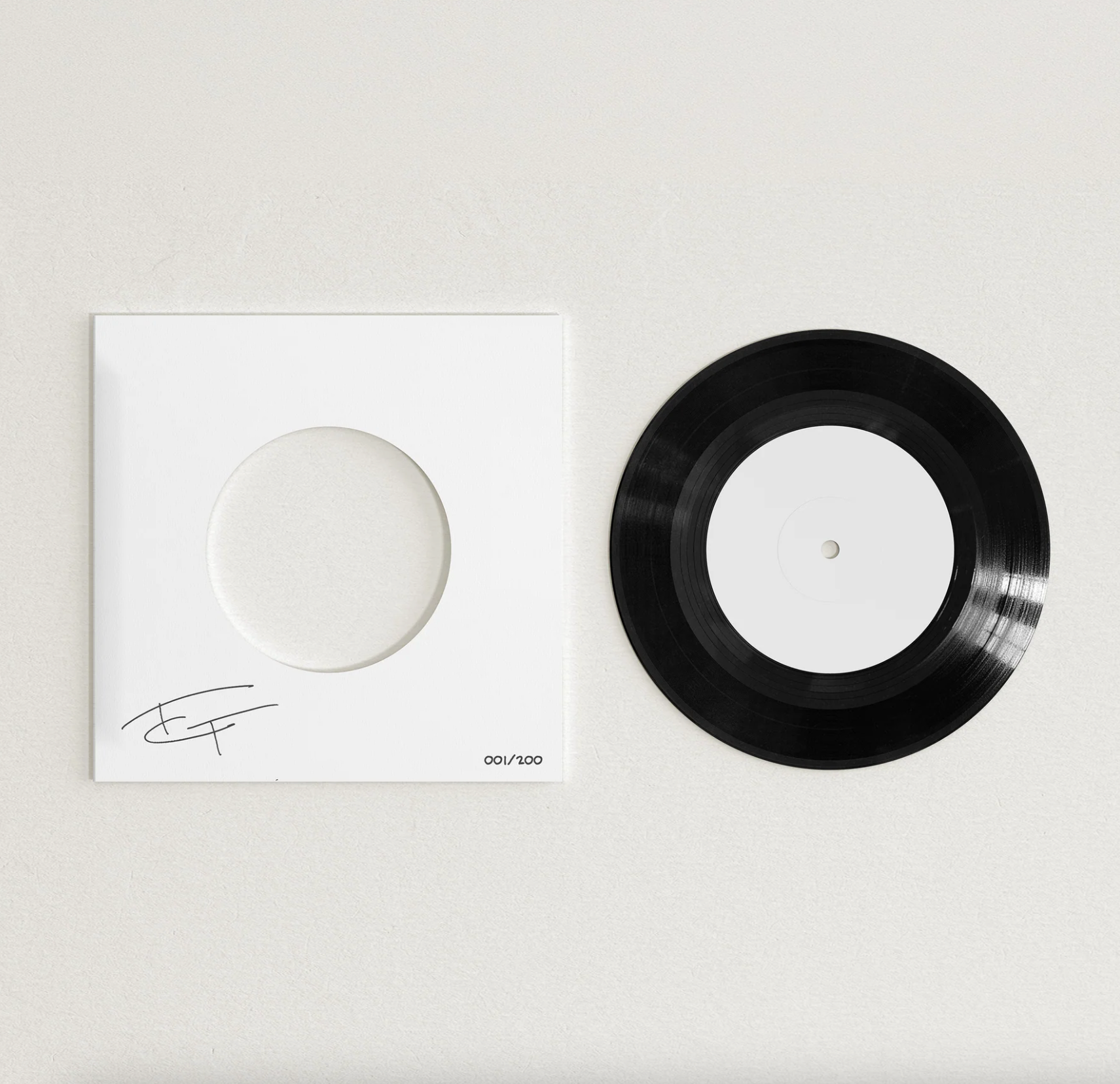 A white, signed, square record sleeve with a circular cutout on the left side and a black vinyl record on the right side. The record has a white label in the center.
