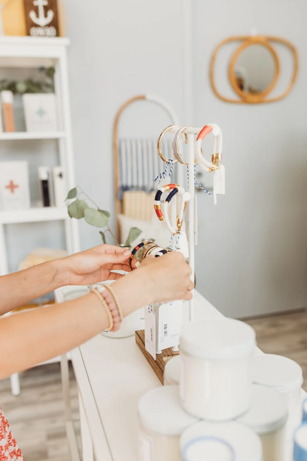 Person adjusting various types of bracelets hanging from a bracelet stand